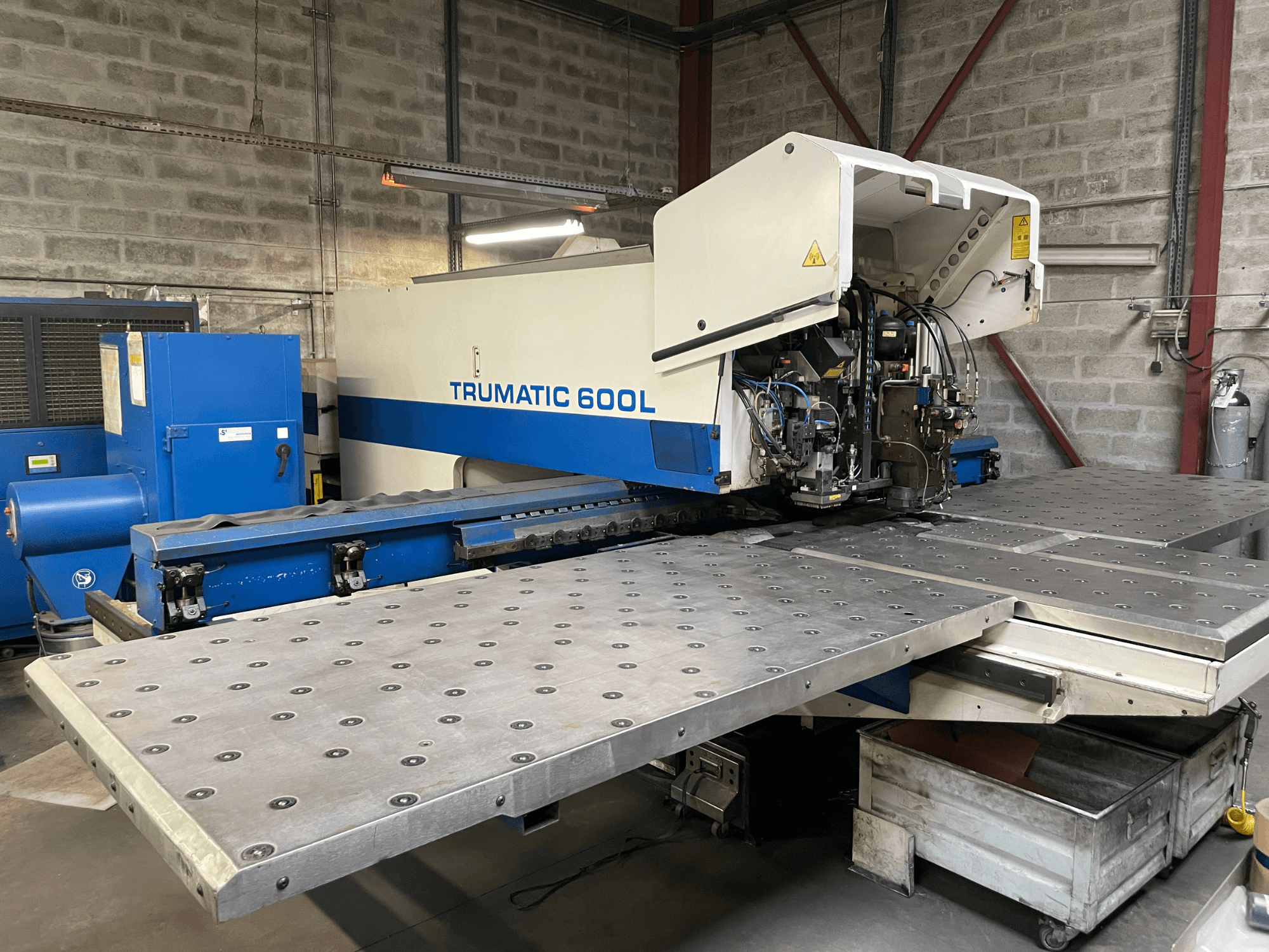 Laserový řezací stroj CO2 TRUMPF TRUMATIC TC 600L, pohled zepředu s viditelným stolem pro řezání kovů a ovládacím panelem.