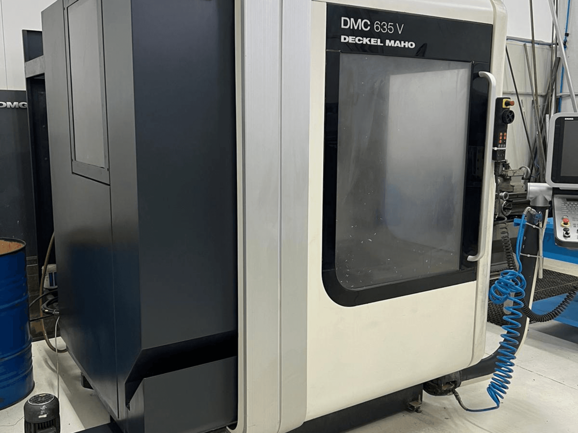 Frézka DMC 635 V od firmy Deckel Maho, boční pohled ukazuje ovládací panel a částečně otevřené přístupové dveře.