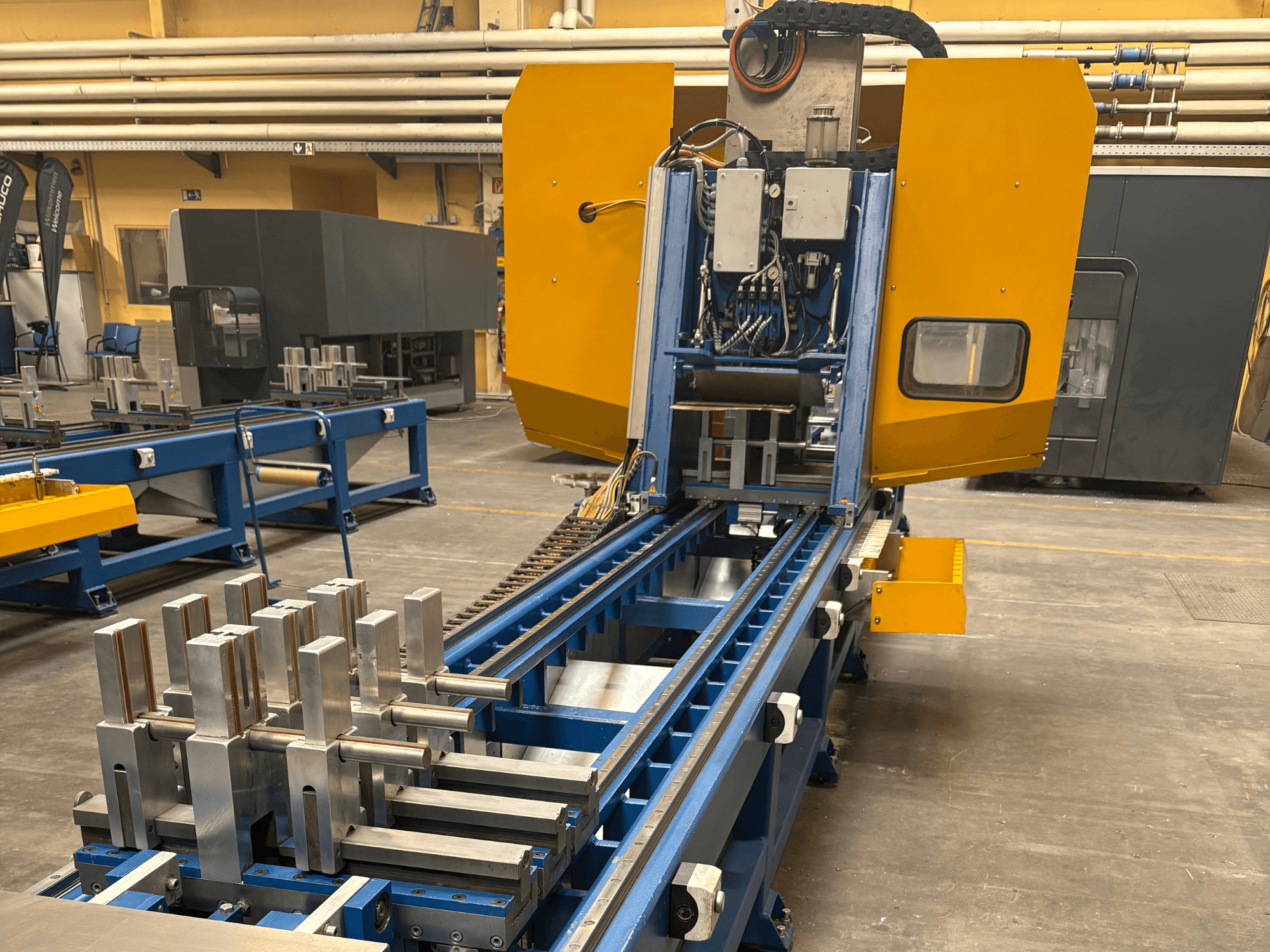 Pohled zepředu na univerzální obráběcí centrum SCHÜCO PBX AL s kovovými obrobky na modrém obráběcím loži.