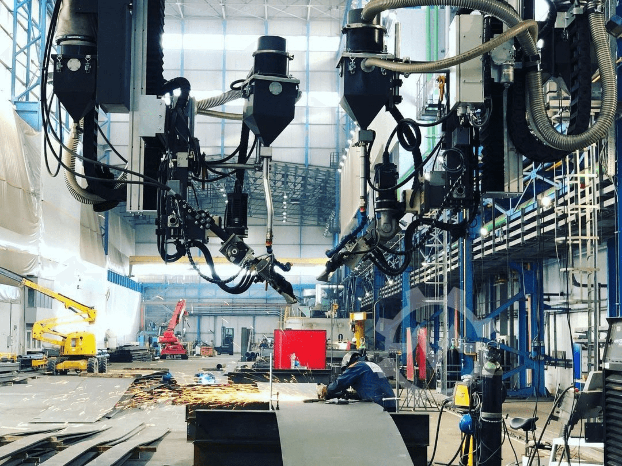 Robotický řezací stroj v průmyslovém prostředí s létajícími jiskrami, pohled z boku; s několika nástavci a hadicemi.