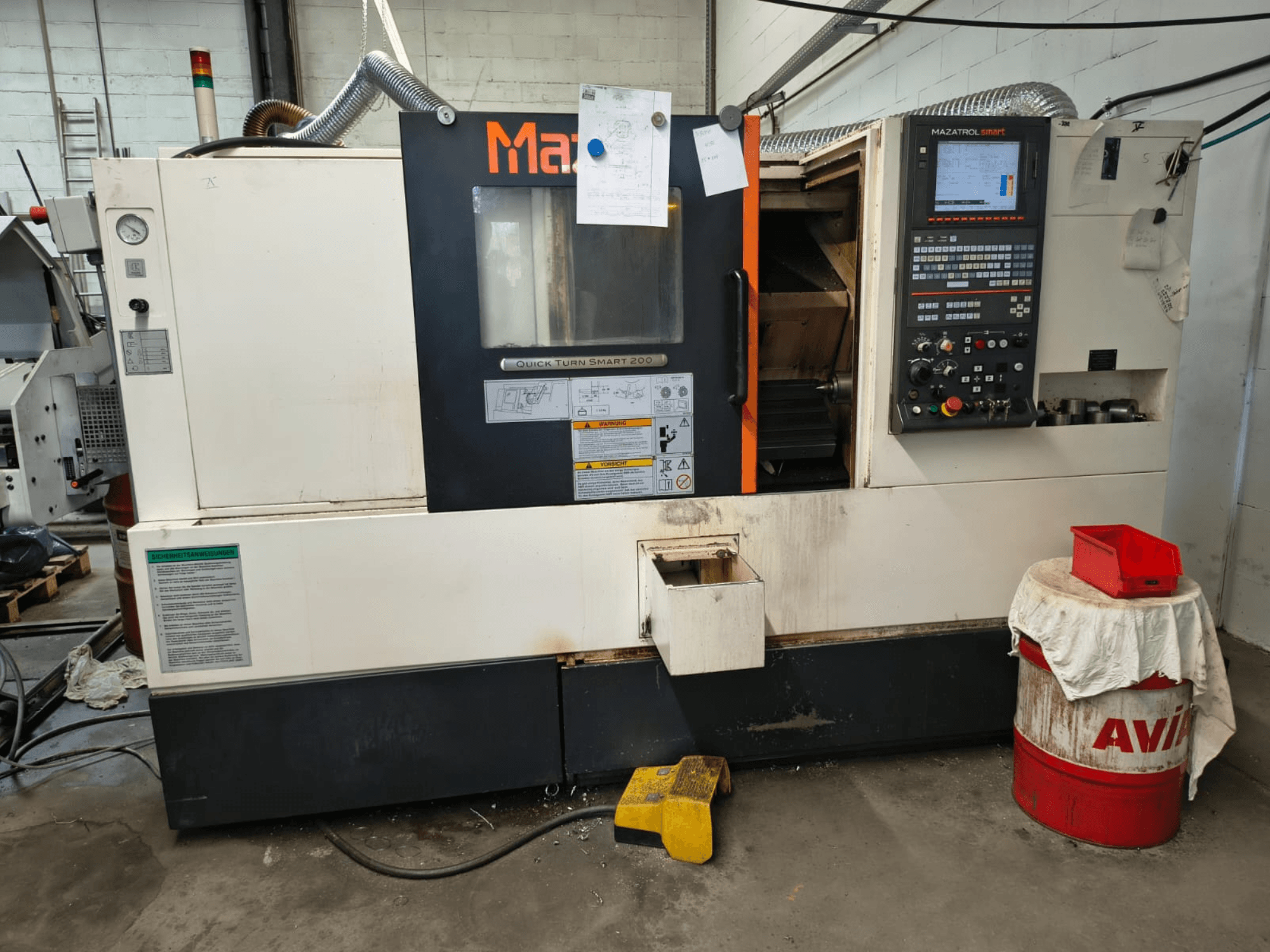Mazak Quick Turn Smart 200, horizontální soustruh, pohled zepředu s viditelným ovládacím panelem, nádrží na chladicí kapalinu a označeními.