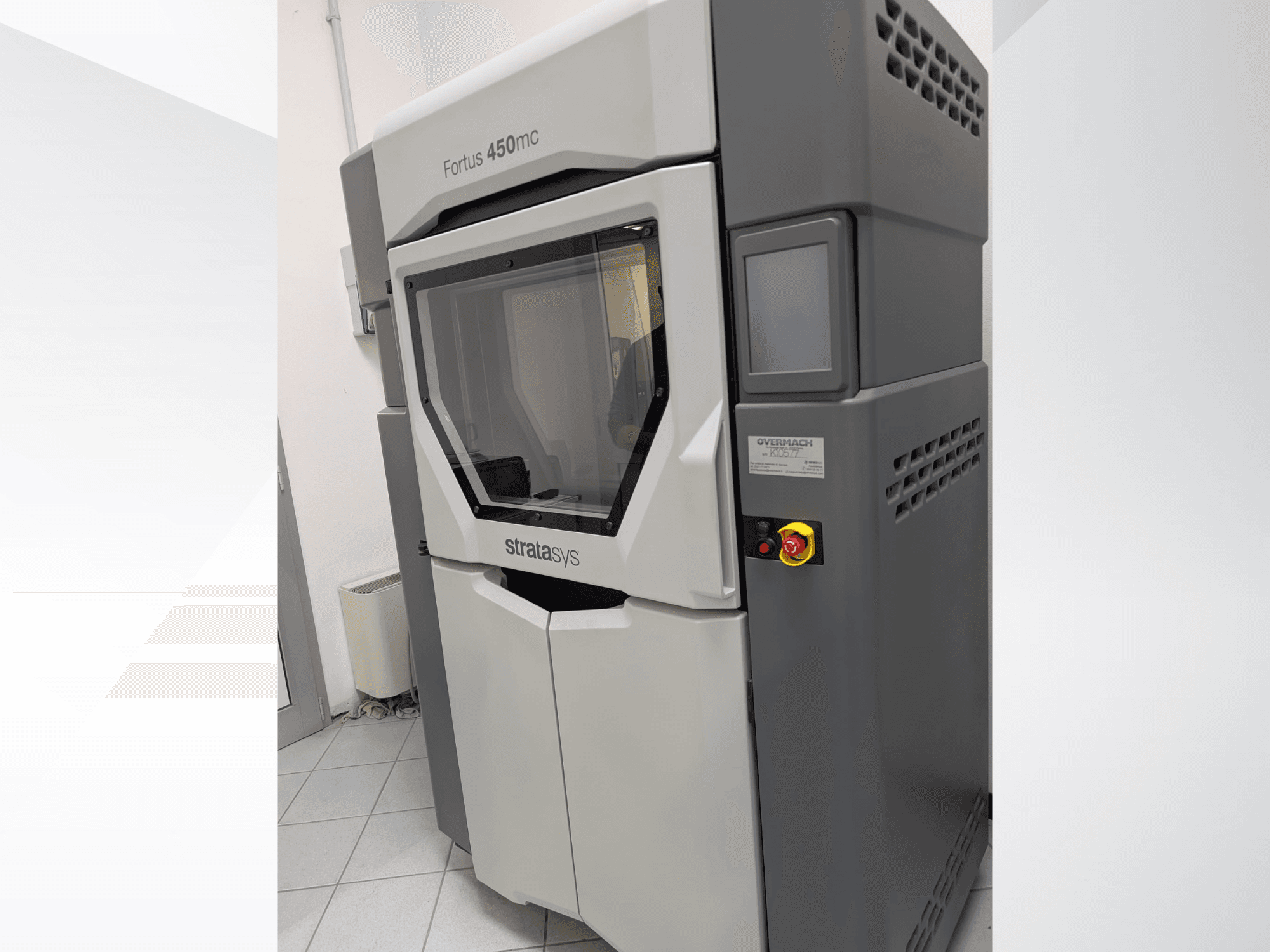 Plastová 3D tiskárna Fortus 450mc v bočním pohledu, s průhledným předním panelem a ovládacími tlačítky na boku.