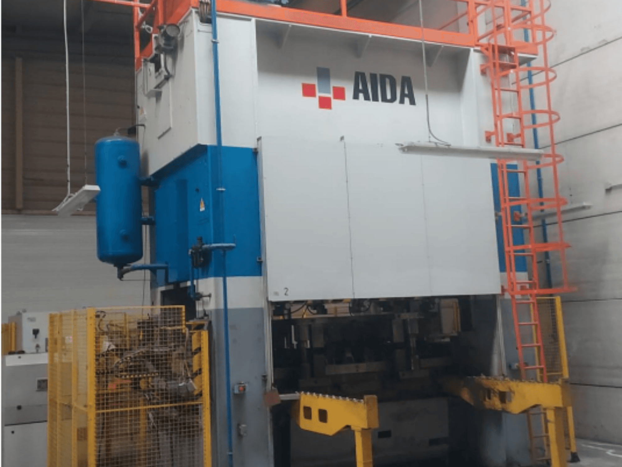 Mechanický lis AIDA 315/2MR/LD/TE 3, pohled zepředu s modrobílým tělesem, žlutou základnou a bezpečnostní klecí.