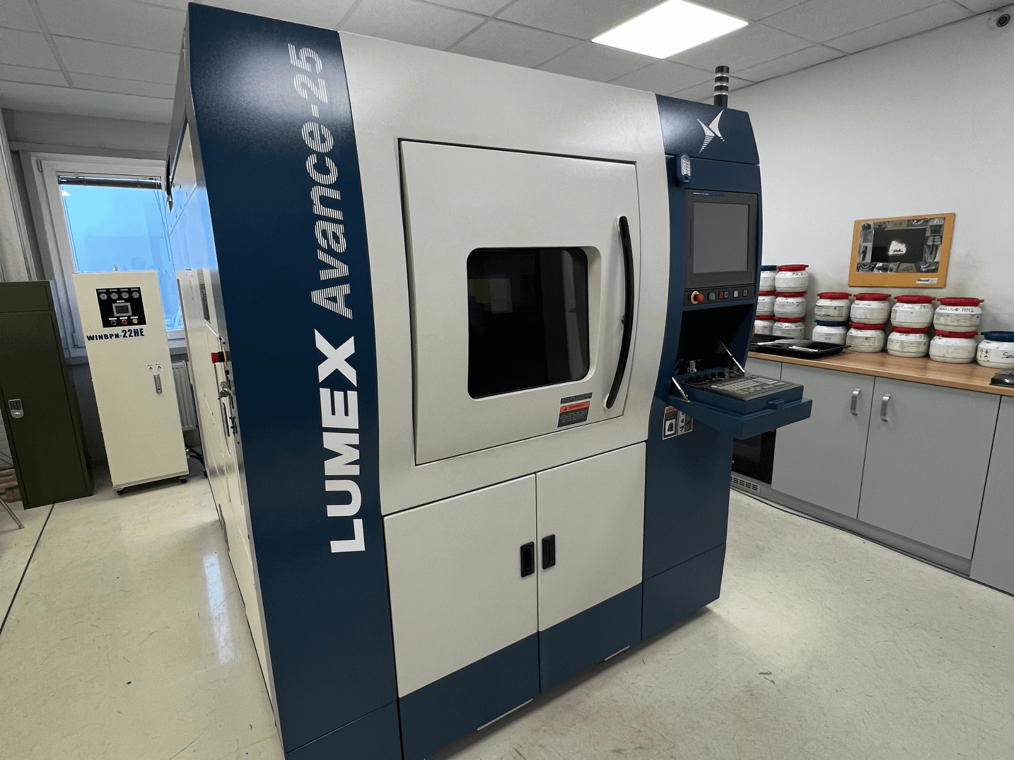 3D tiskárna LUMEX Avance-25 v laboratoři, pohled zepředu. Ovládací panel s viditelnou obrazovkou a tlačítky, zařízení v pozadí.