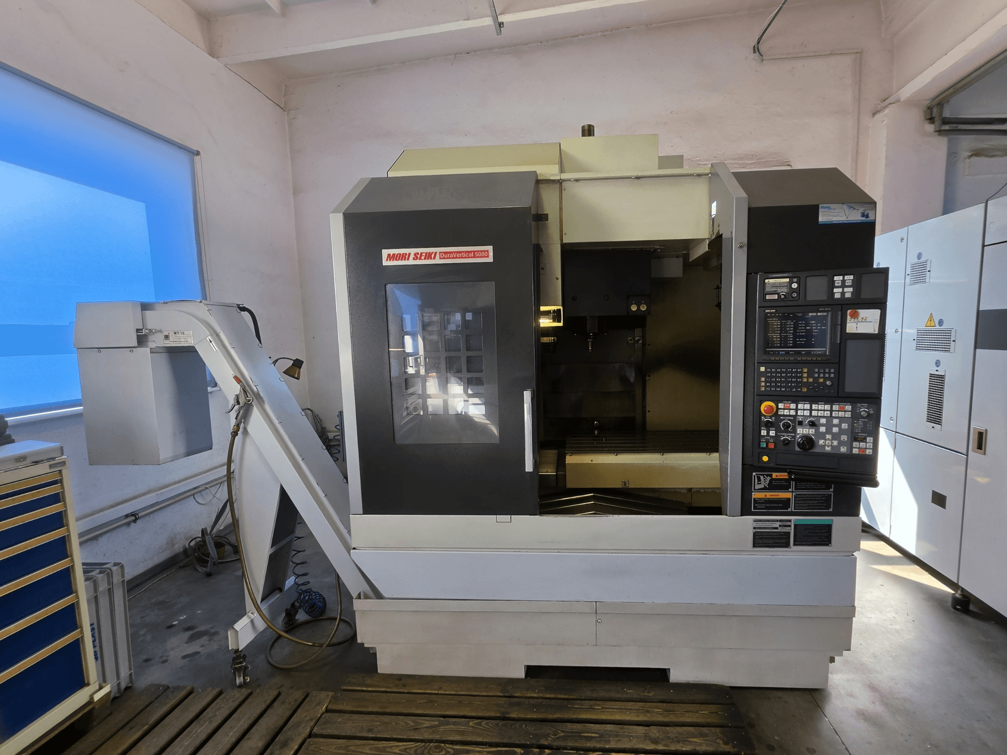 Vertikální obráběcí centrum MORI SEIKI DuraVertical 5080, pohled zepředu znázorňující ovládací panel, vřeteno a držák nástroje.