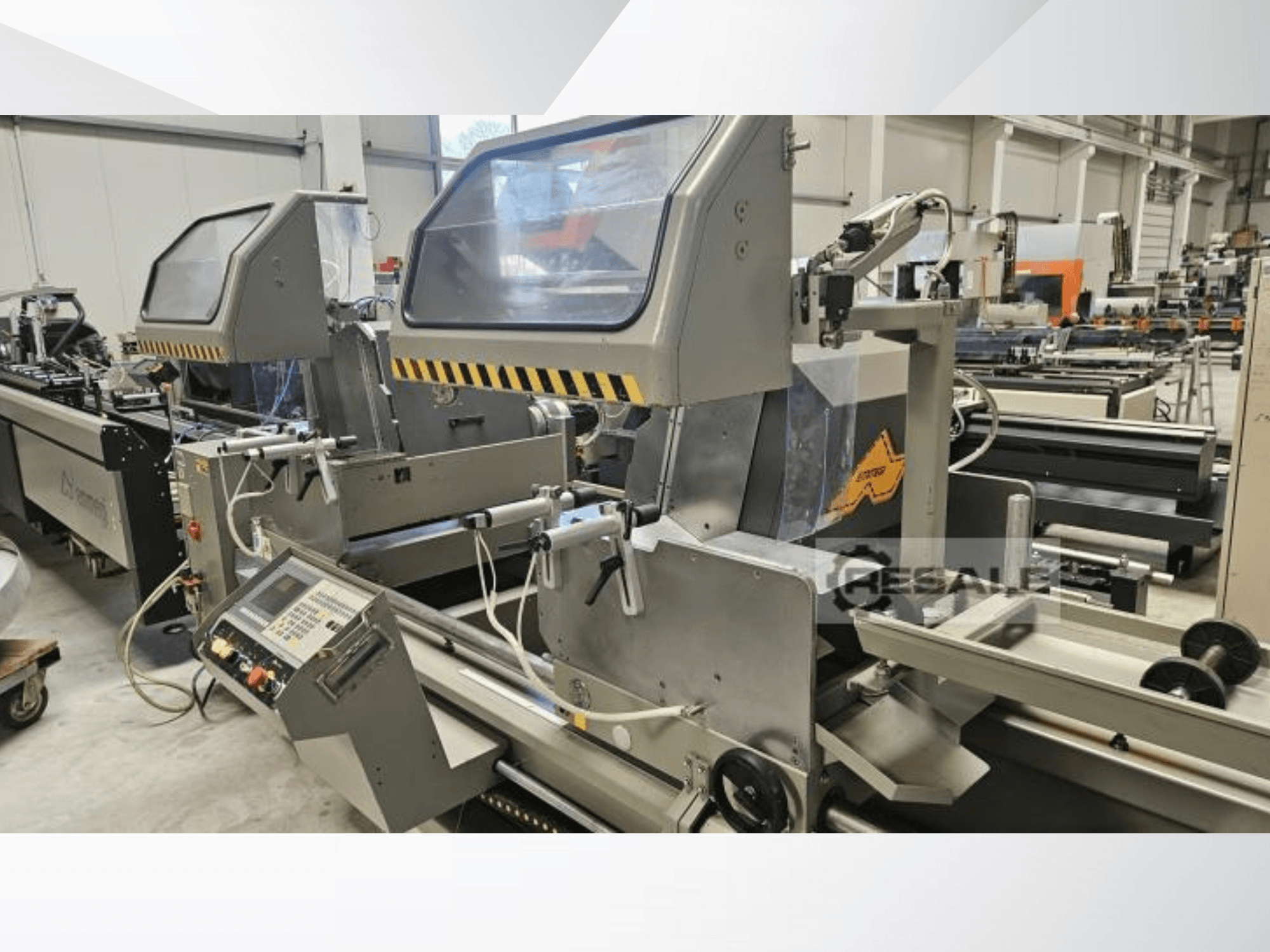 Dvojitá pila v továrním prostředí; pohled zepředu ukazuje ovládací panel, skleněné kryty a řezné komponenty.