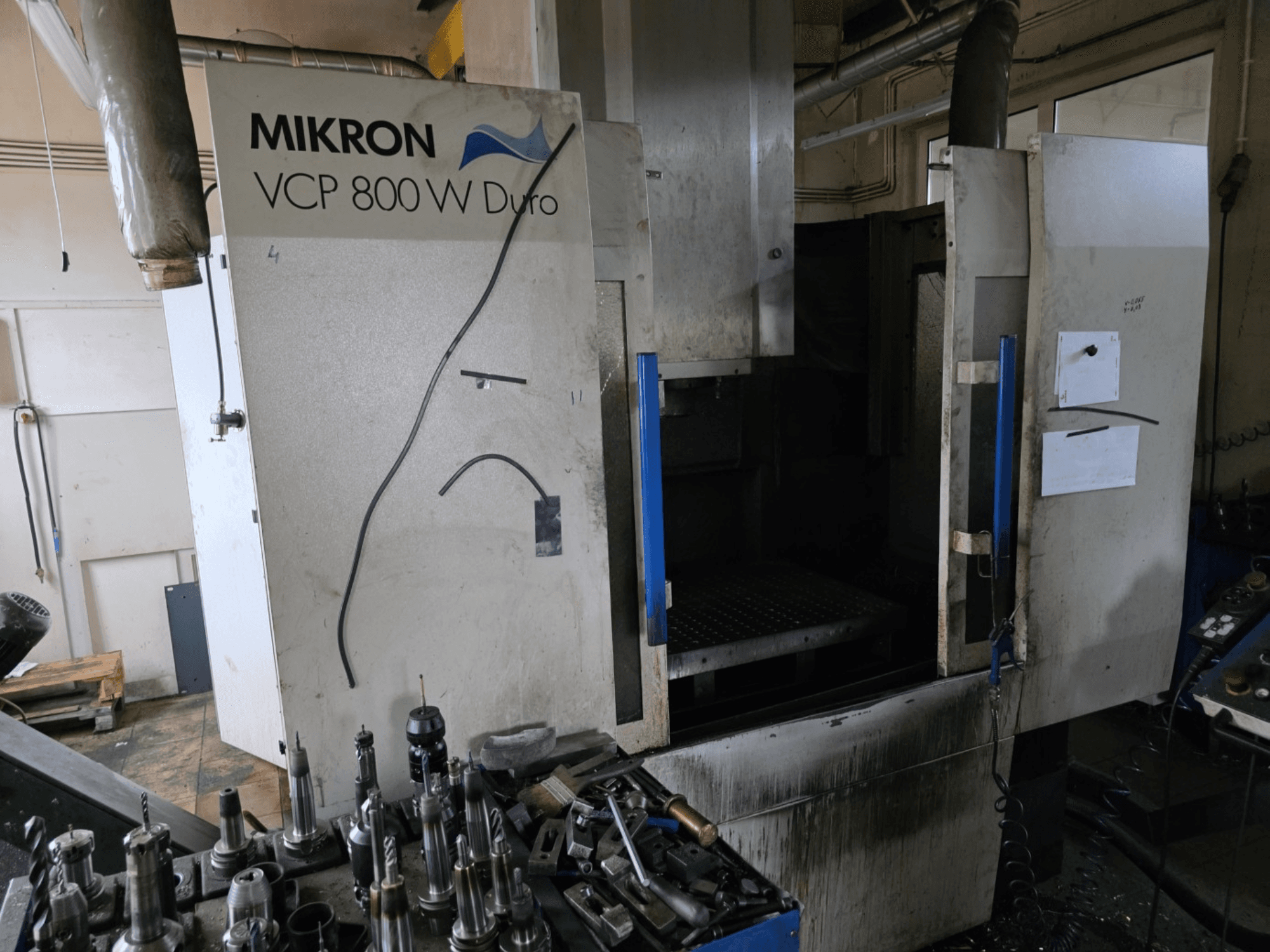 Frézka Mikron VCP 800 W Duro zobrazená z bočního pohledu, v popředí jsou vidět nástroje a ovládací prvky.