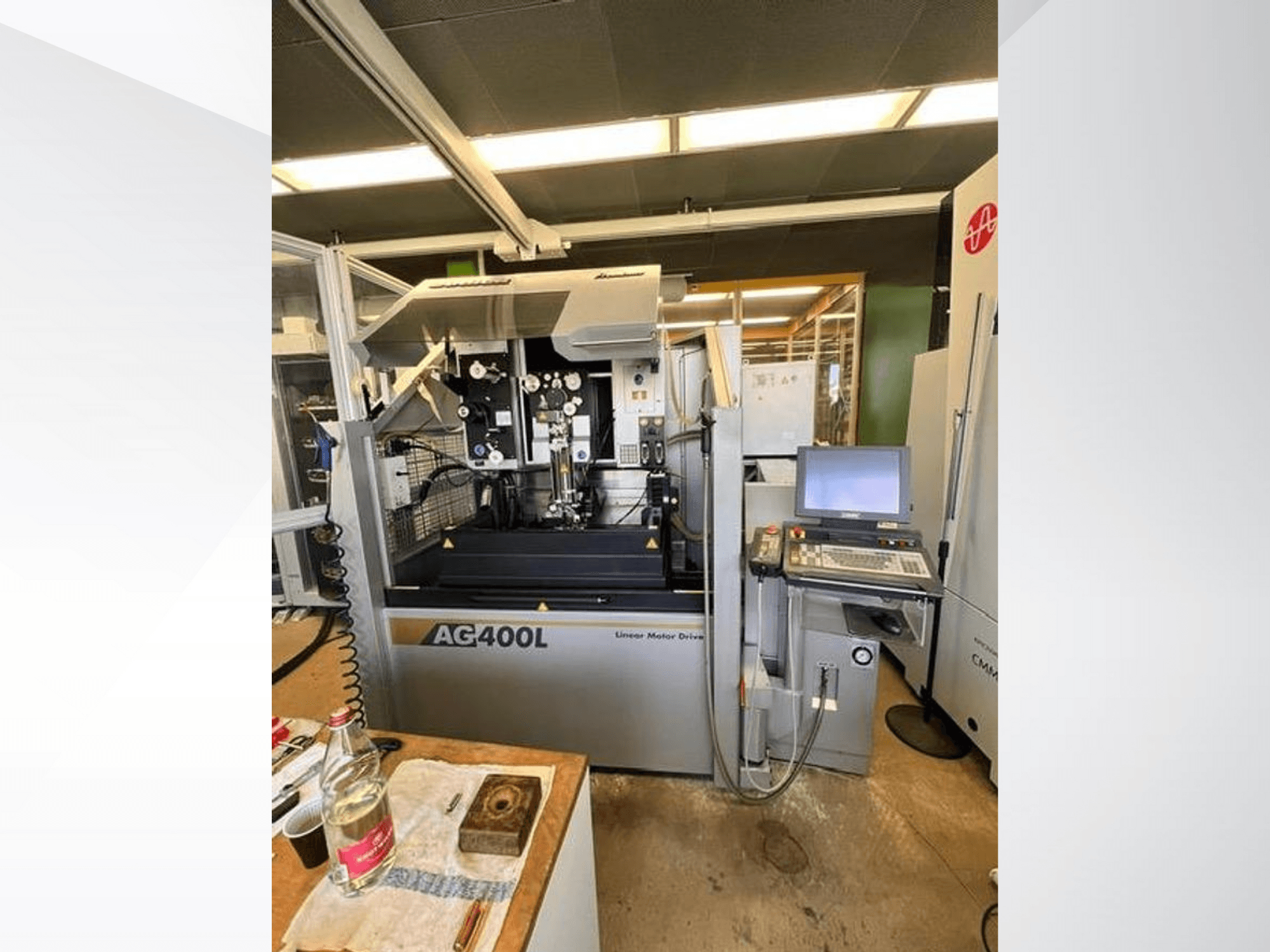 Stroj s lineárním motorovým pohonem AG400L, pohled zepředu, s viditelným ovládacím panelem a pracovním prostorem s bezpečnostními prvky.