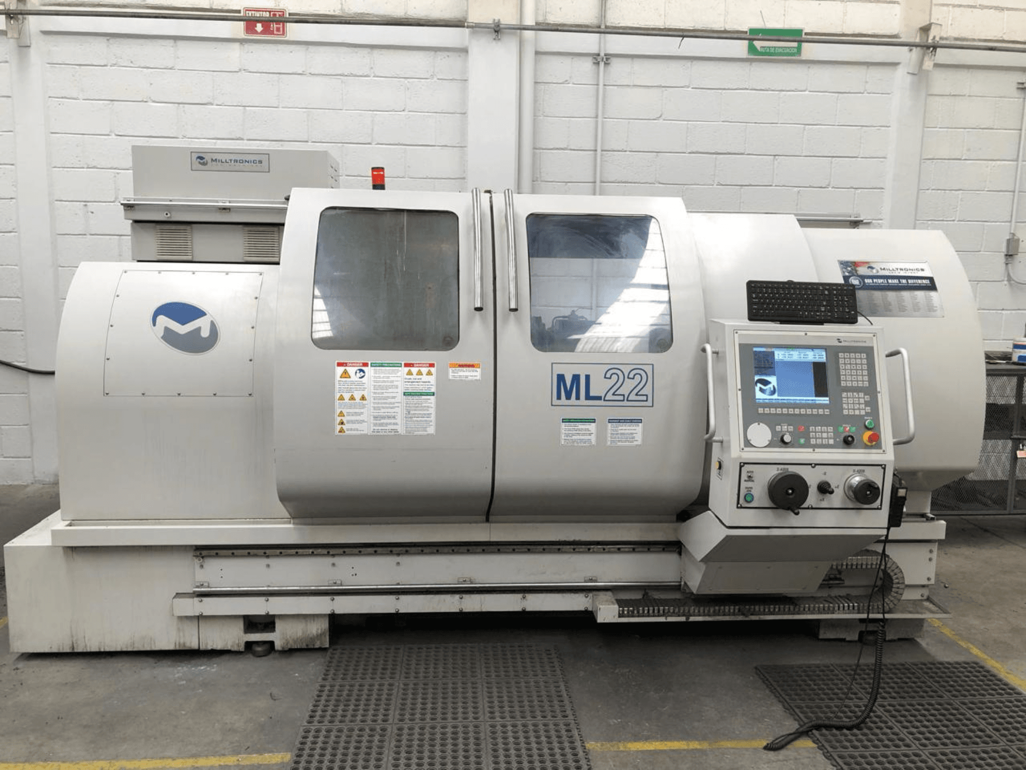 Vertikální obráběcí centrum MILLTRONICS RH 20, čelní pohled zobrazující ovládací panel, logo značky a bezpečnostní štítky na stroji.
