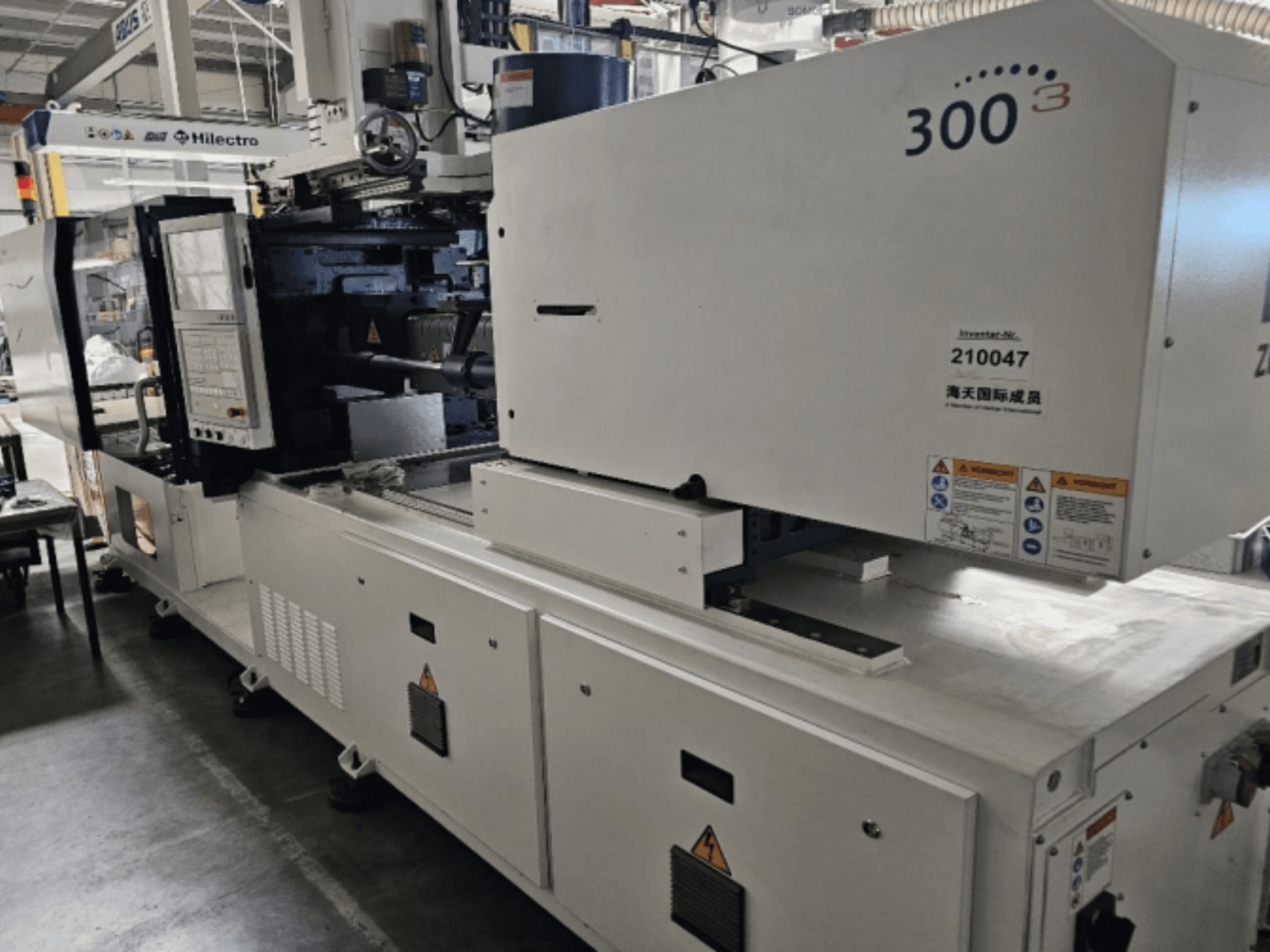 Vstřikovací stroj značky Zhenjing, model 300, pohled zepředu s viditelným ovládacím panelem a bezpečnostními výstražnými štítky.