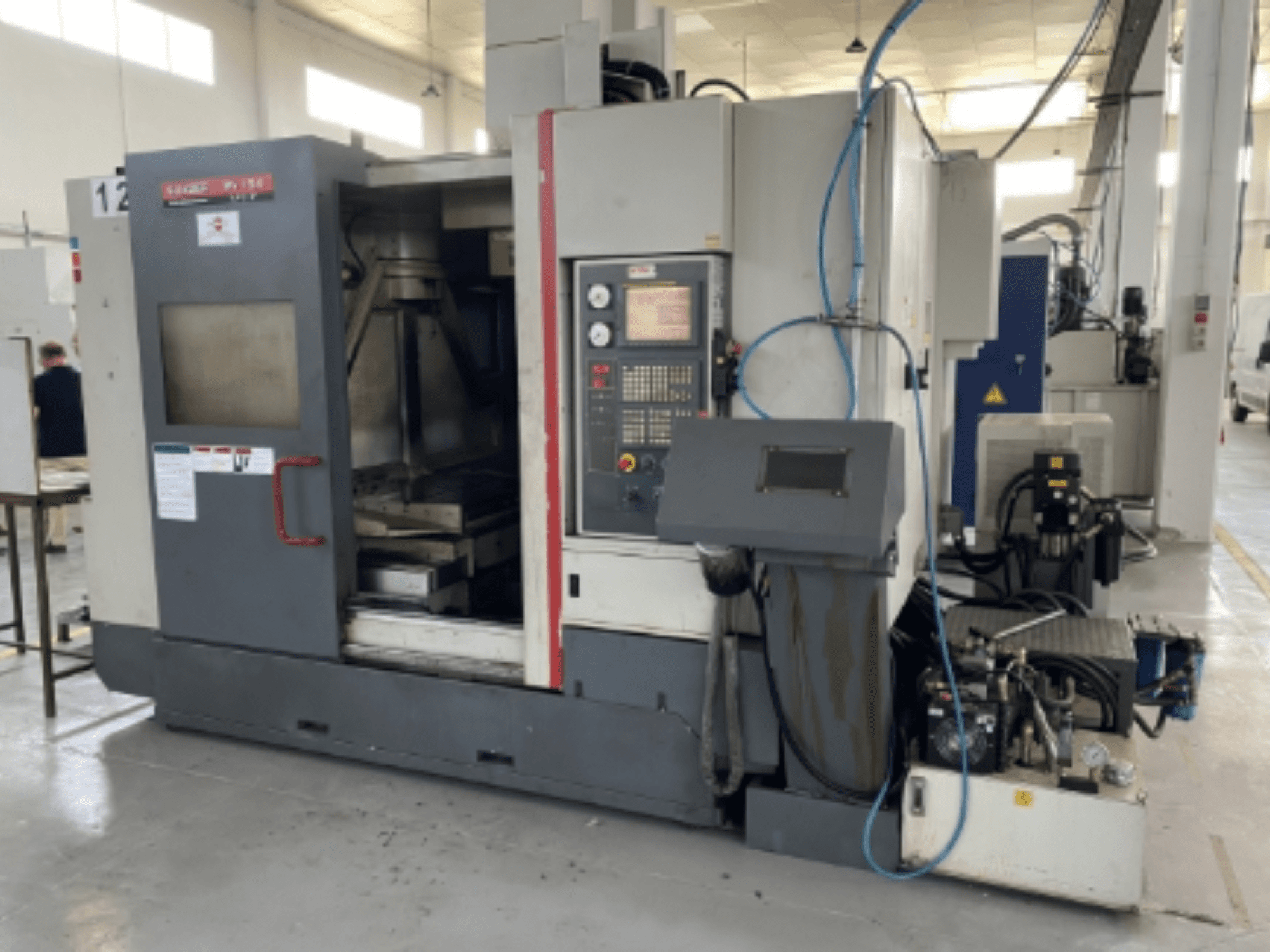 Vertikální obráběcí centrum Quaser MV154APC-912, čelní pohled zobrazující ovládací panel, otevřené dveře a součásti stroje.