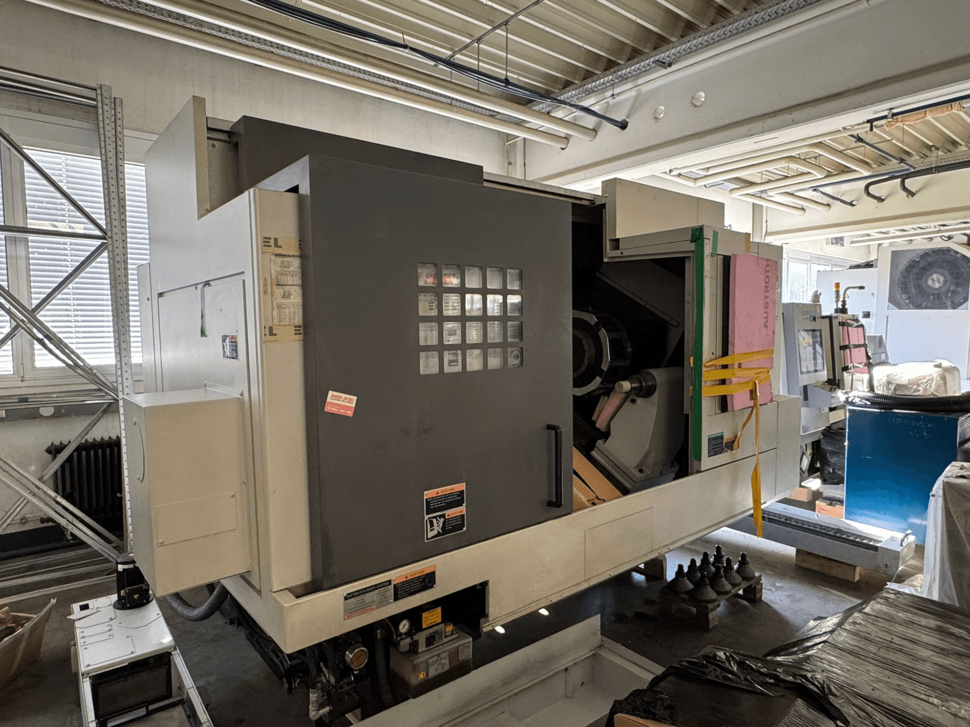Horizontální soustruh MORI SEIKI NL 3000 MC/700, pohled zepředu s ovládacím panelem, úložným prostorem a ochranným krytem.