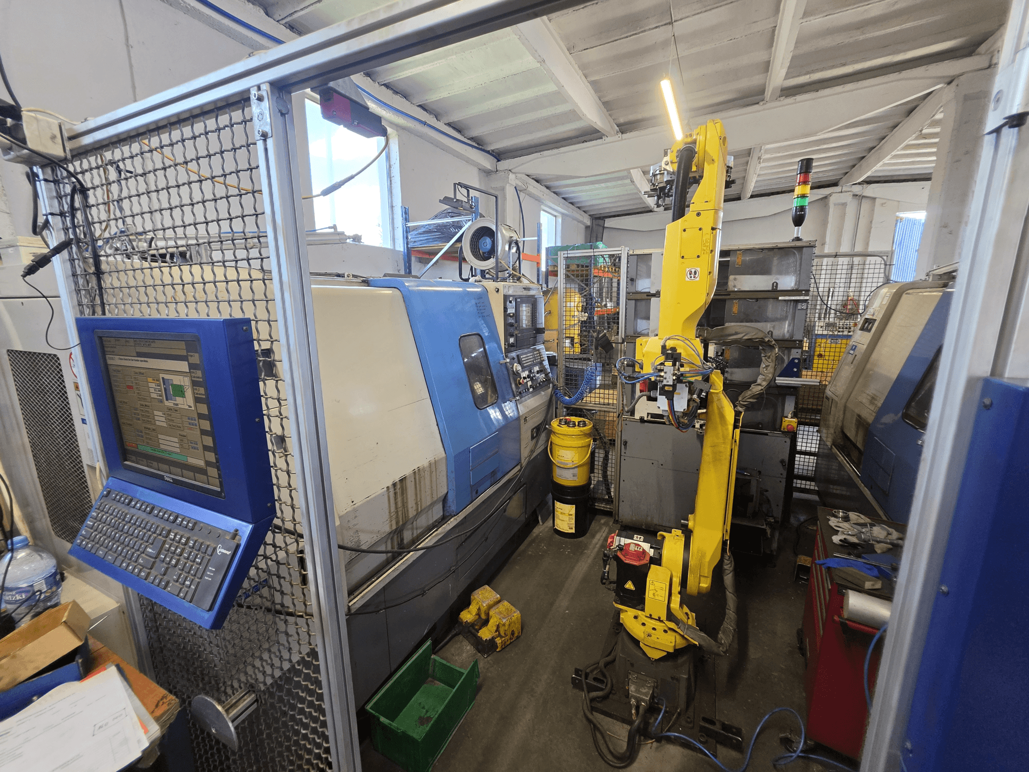 Horizontální soustruh Hyundai HIT-200C s robotem FANUC M-20iA, pohled zepředu znázorňující ovládací rozhraní a uspořádání stroje.