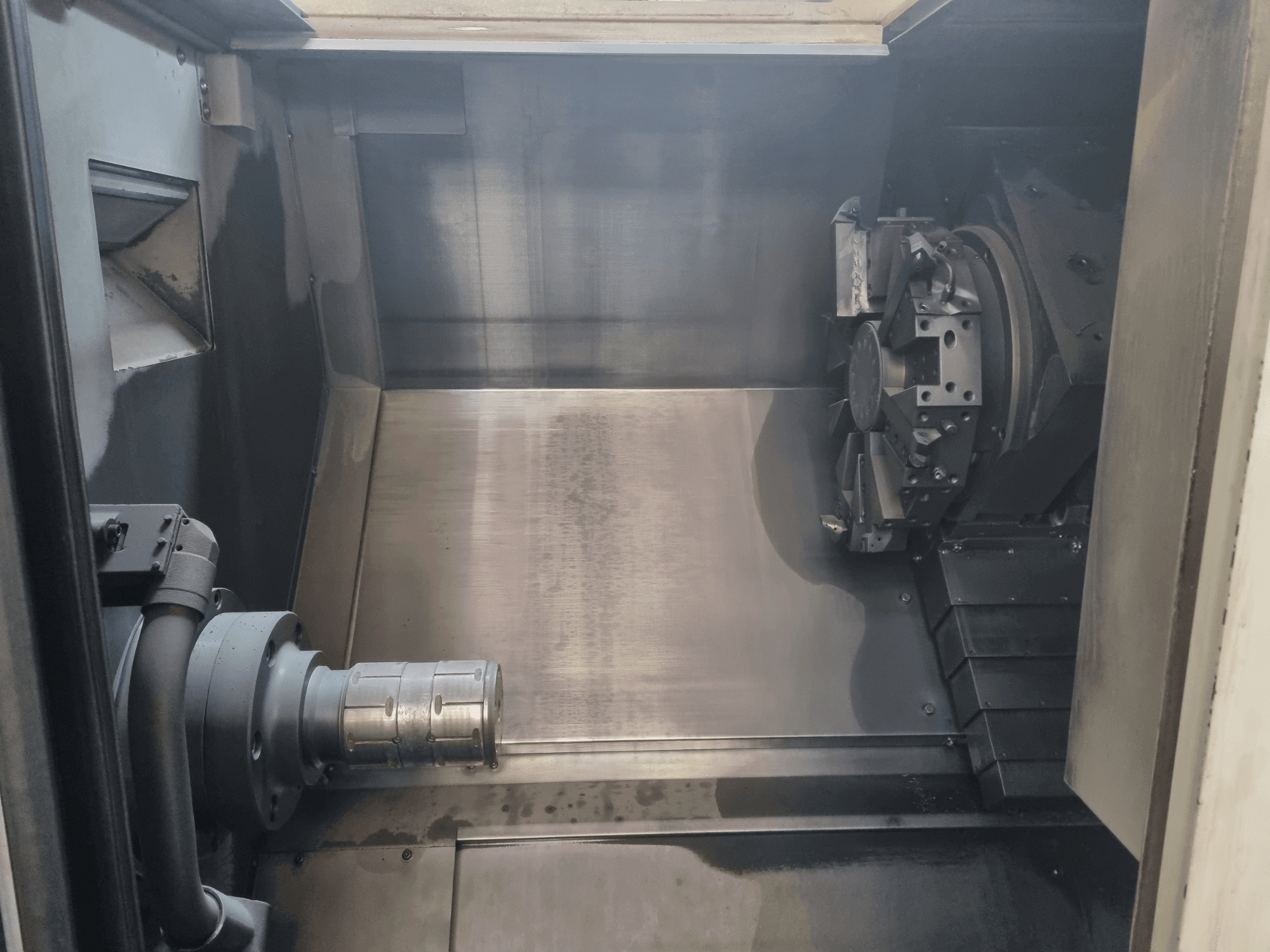 Pohled do interiéru CNC stroje s kovovým pracovním prostorem, držákem nástrojů a sklíčidlem; zdůrazňuje přesnost konstrukce.