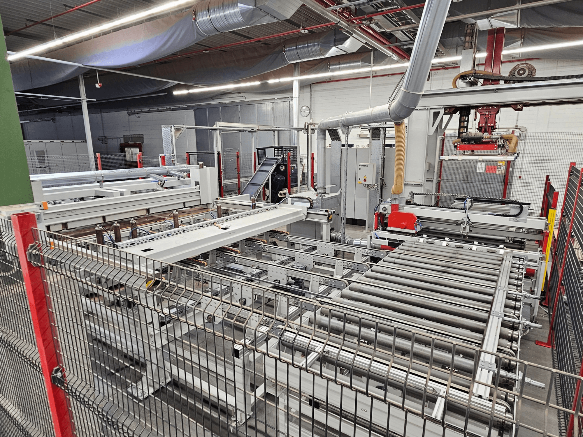 Panelová pila HOLZMA HPP81-3200 zobrazená v čelním pohledu, s dopravními válečky a strojními součástmi v dílenském prostředí.