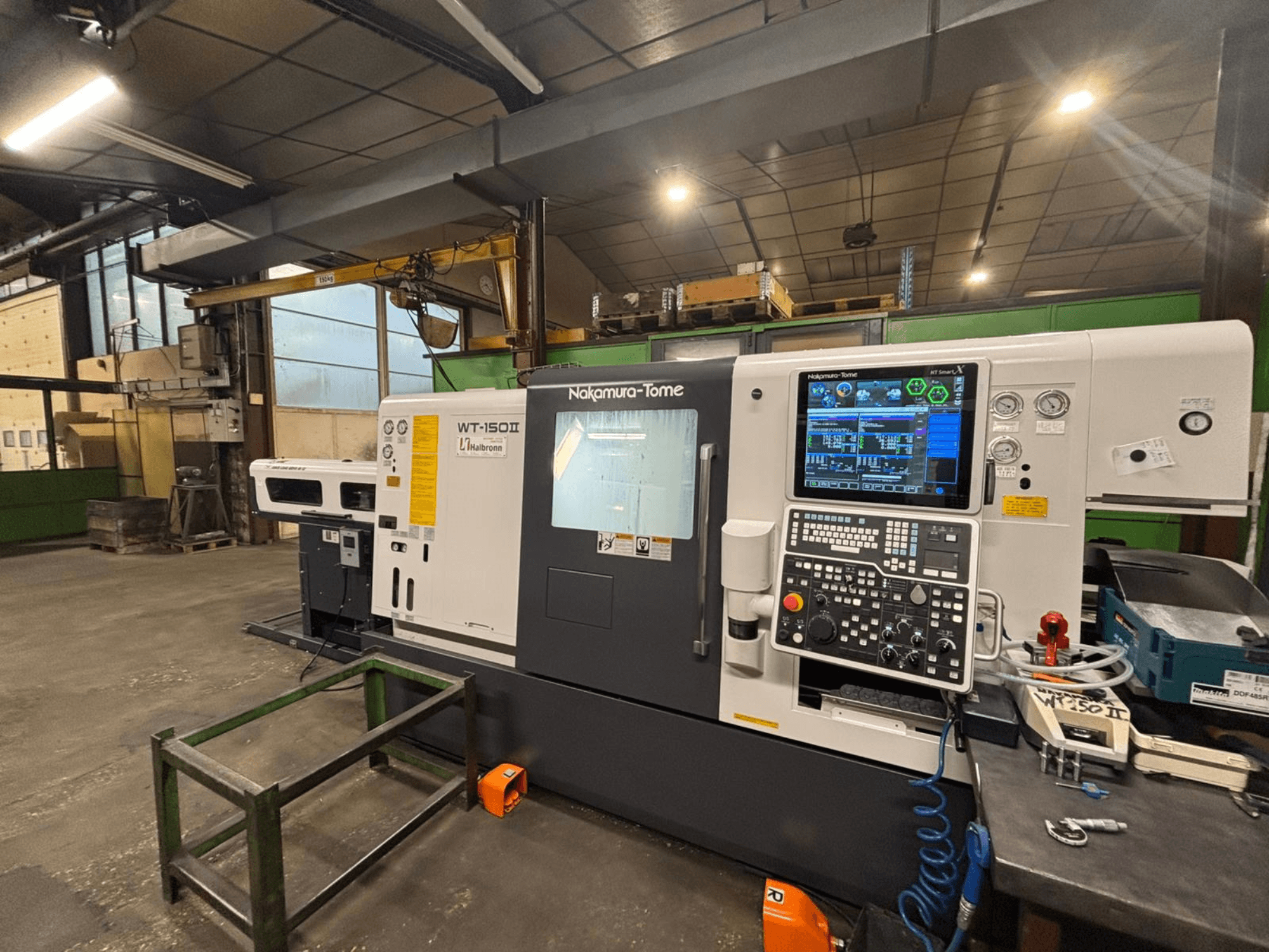 Stroj Nakamura-Tome WT-150II, pohled zepředu, s viditelným ovládacím panelem a nástroji na pracovním stole v dílně.