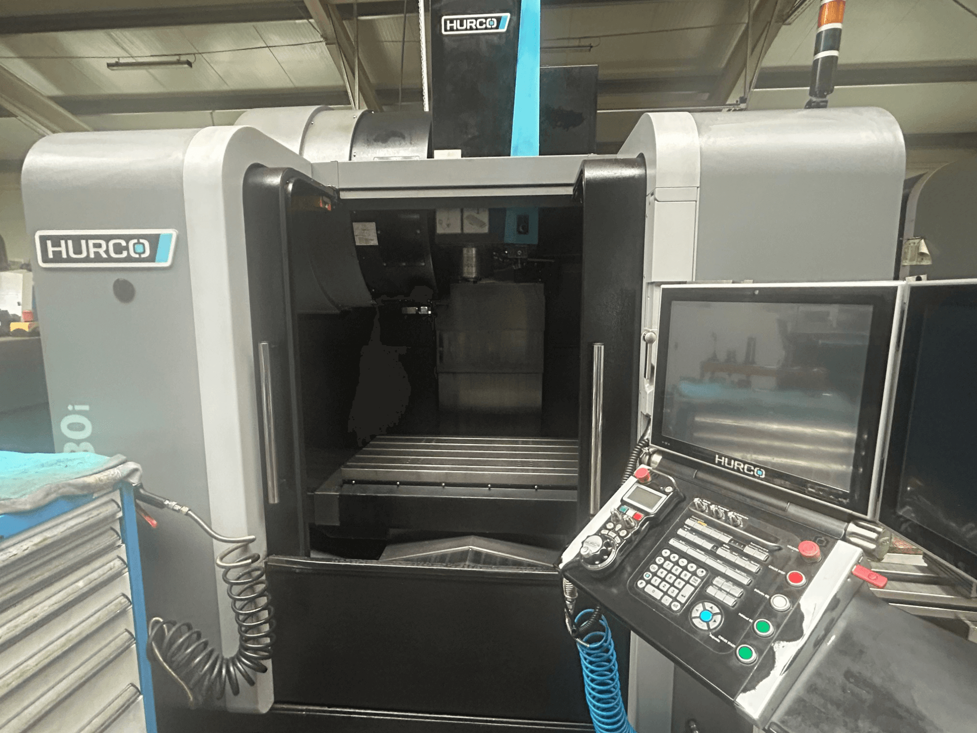 Pohled zepředu na CNC stroj Hurco VM30i, ovládací panel s tlačítky, displej a prostor pro uložení nástrojů.