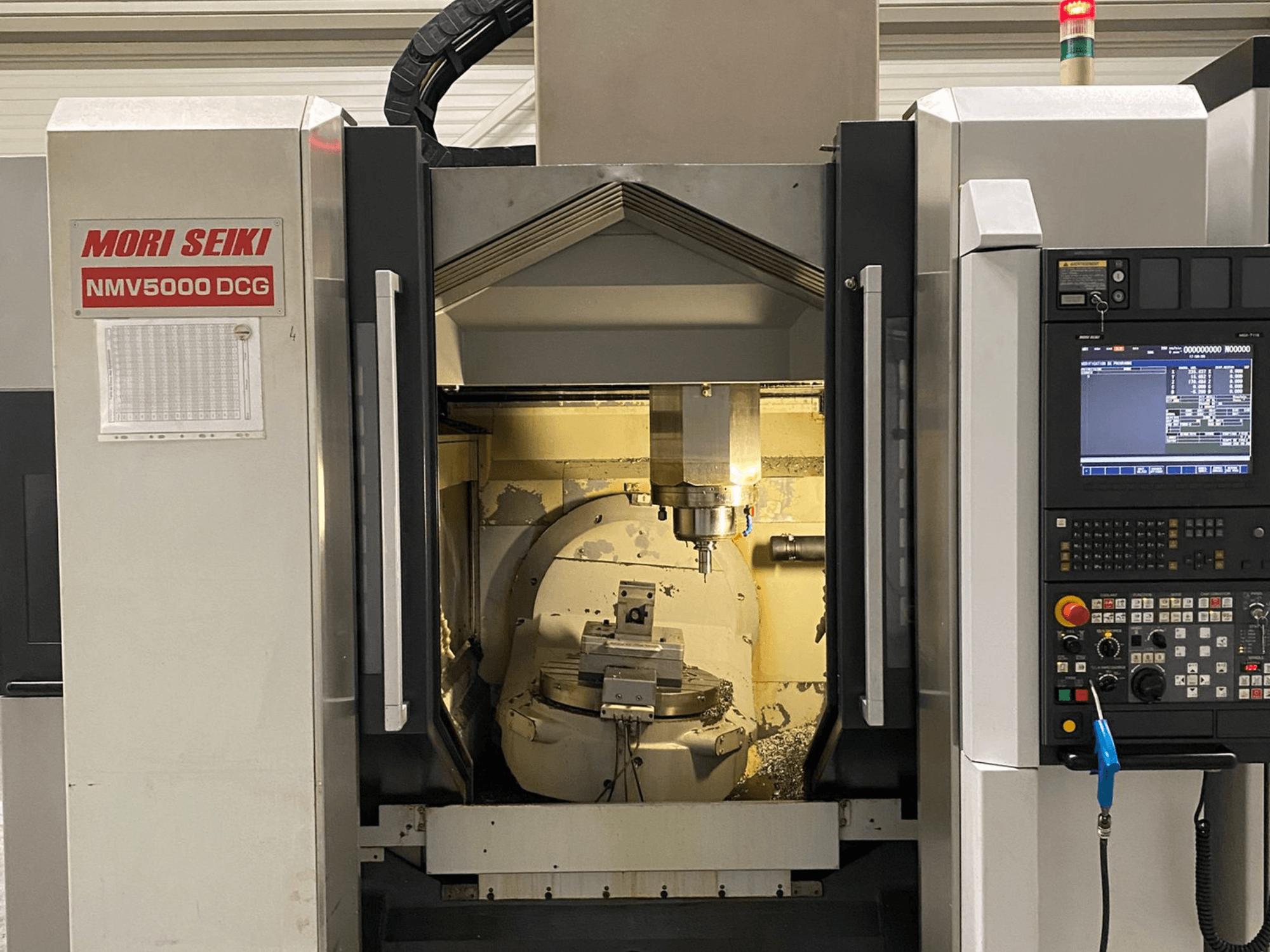 Univerzální obráběcí centrum MORI SEIKI NMV 5000DCG, pohled zepředu na ovládací panel a vnitřní obráběcí prostor.