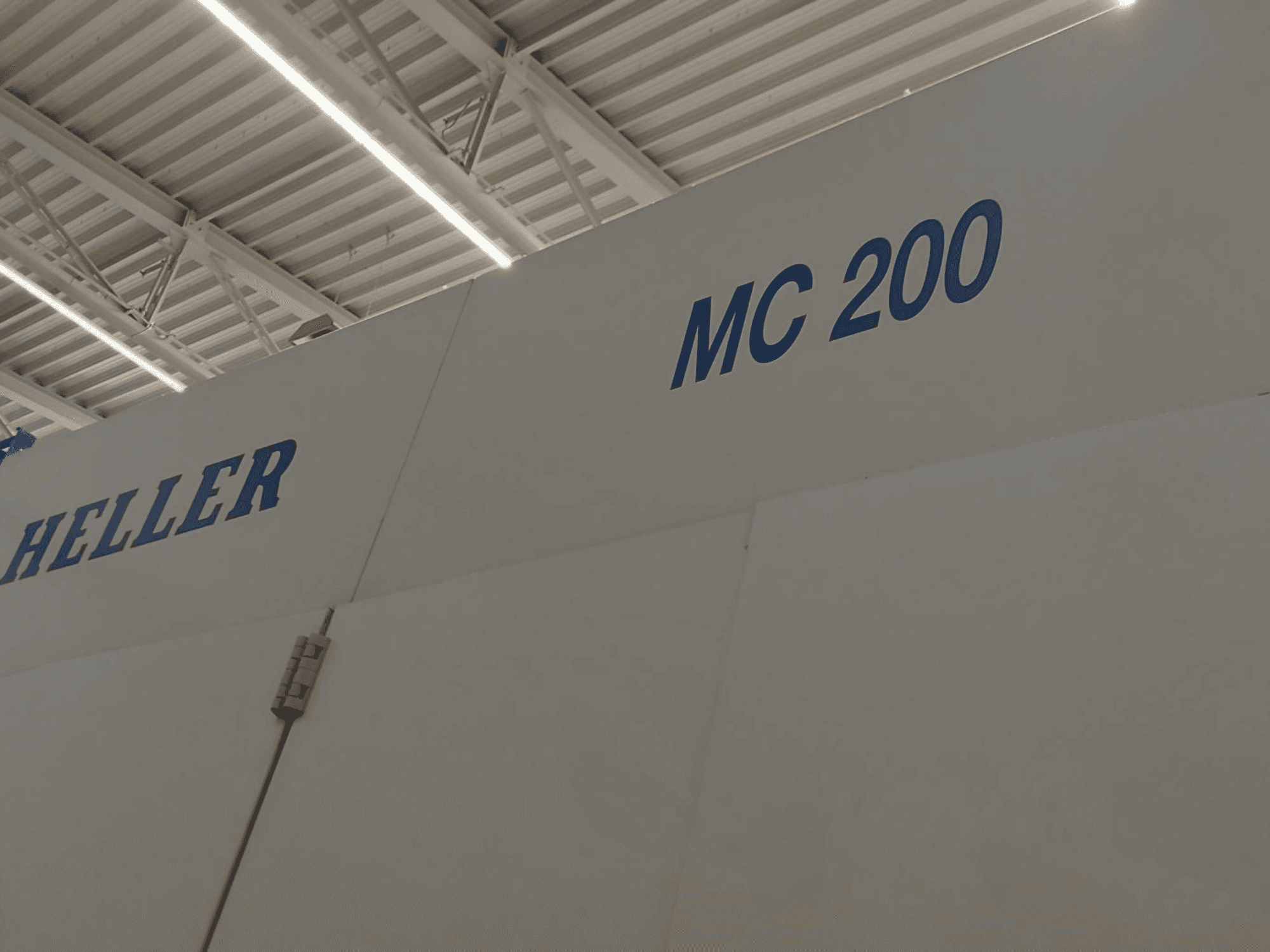 Horizontální obráběcí centrum Heller MC 200, zobrazené z boku, s modrým nápisem značky a modelu na bílé ploše.