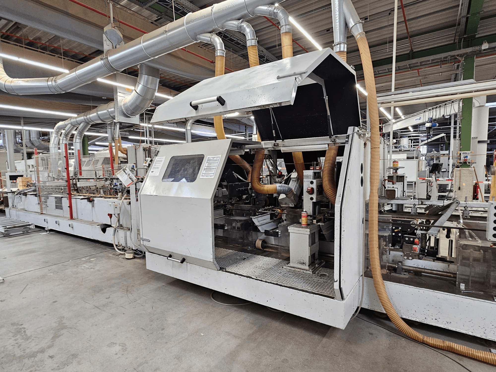 Olepovačka hran HOMAG FG63 v továrním nastavení, boční pohled na provozní součásti a systém odsávání prachu.