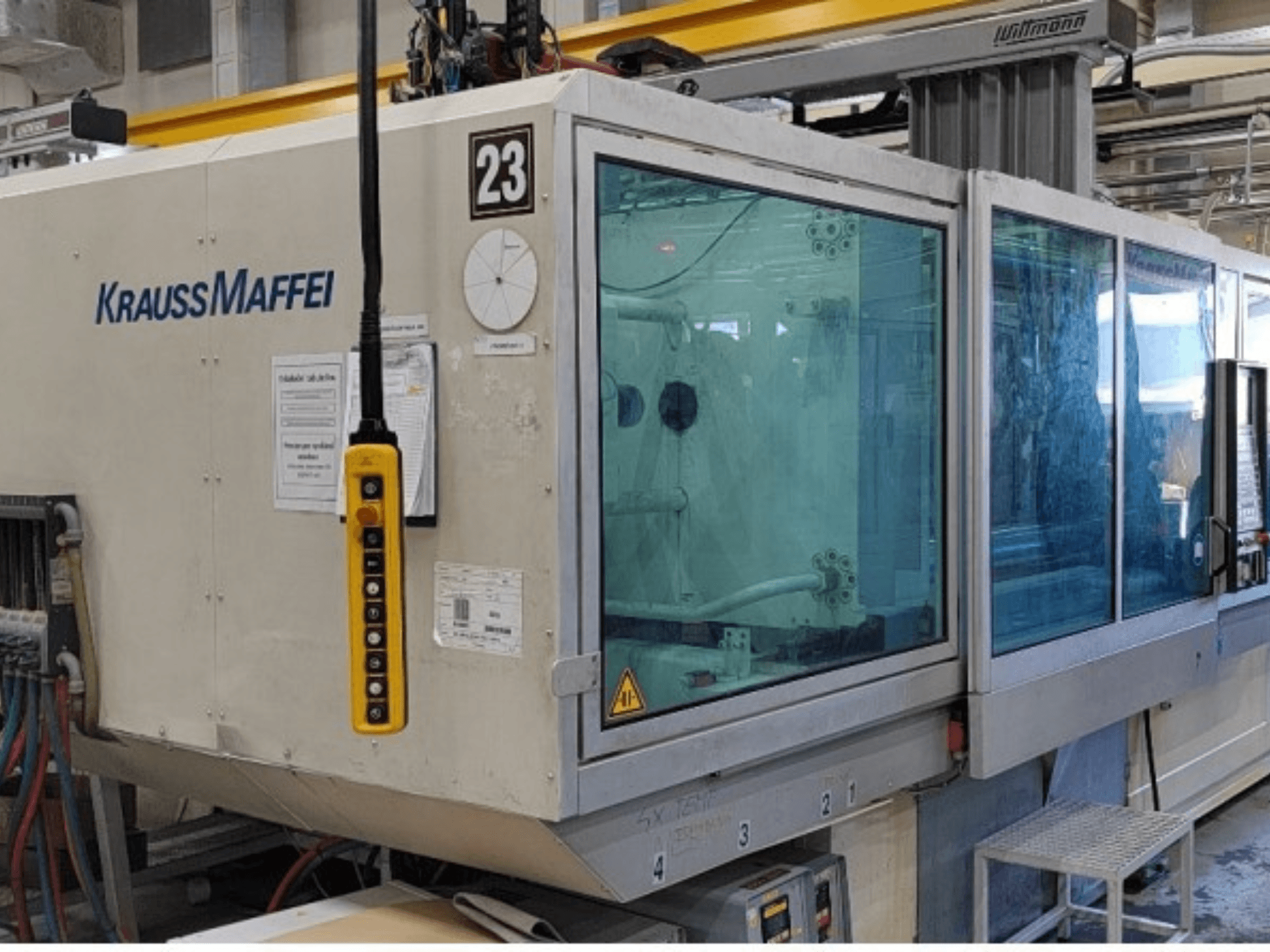 Hydraulický vstřikovací stroj Krauss Maffei KM 350-1900 C2, pohled zepředu s ovládacím panelem a průhledným bezpečnostním krytem.