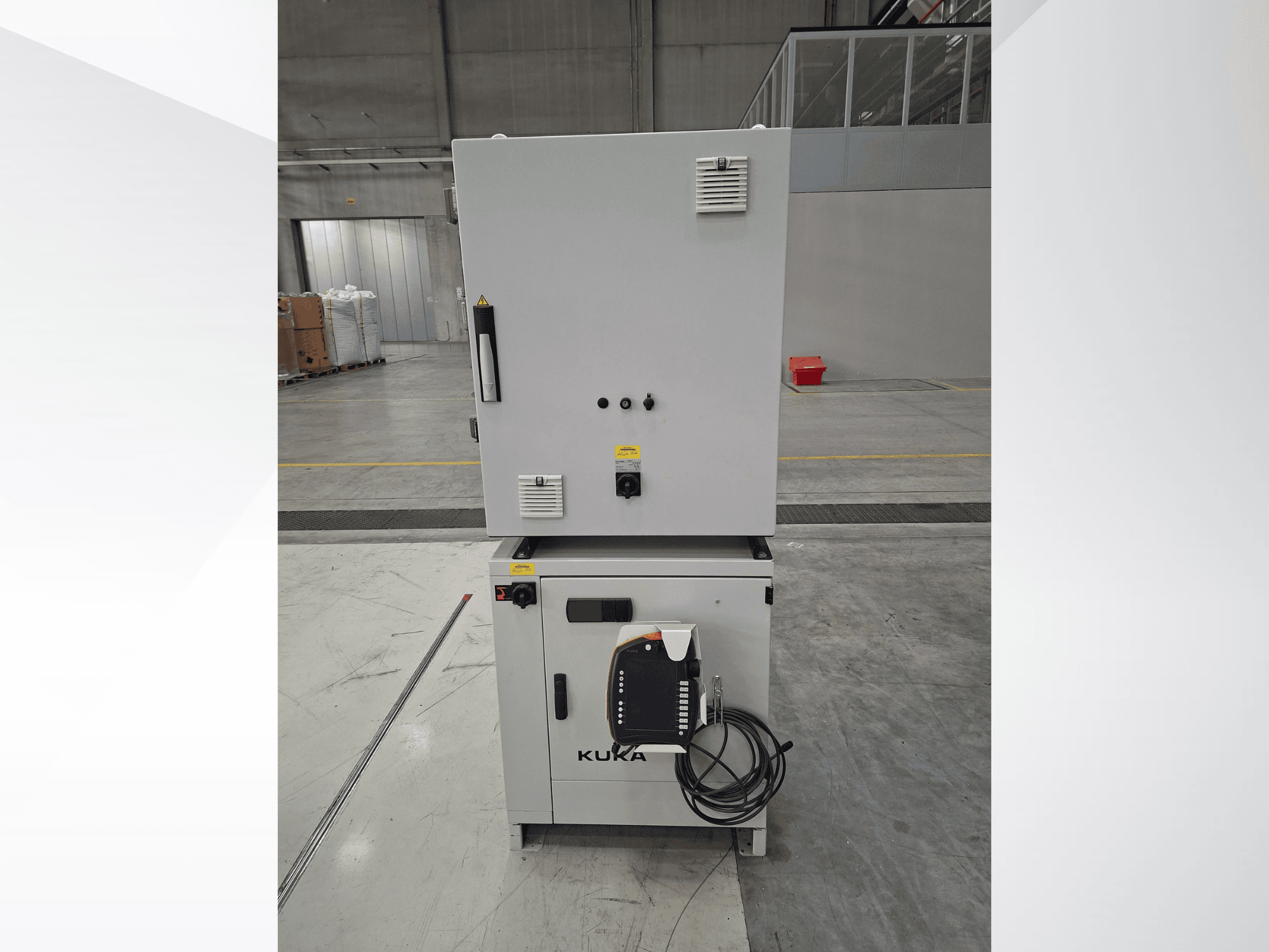 Řídicí jednotka robotického ramene KUKA KR 90 R2700 PRO C4 FLR, pohled zepředu znázorňující ovládací panel a bezpečnostní štítky v prostorném skladu.