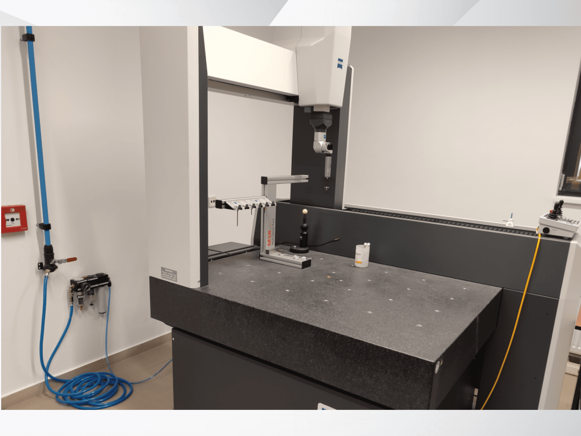 Měřicí zařízení MSR v laboratoři, pohled zepředu na žulový stůl, kalibrační kouli a připojené nástroje.