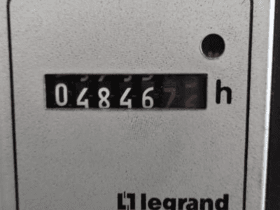 Hodinoměr Legrand s údajem 048467.6, pohled zepředu s červenou kontrolkou a černými číslicemi na světlém pozadí s texturou.