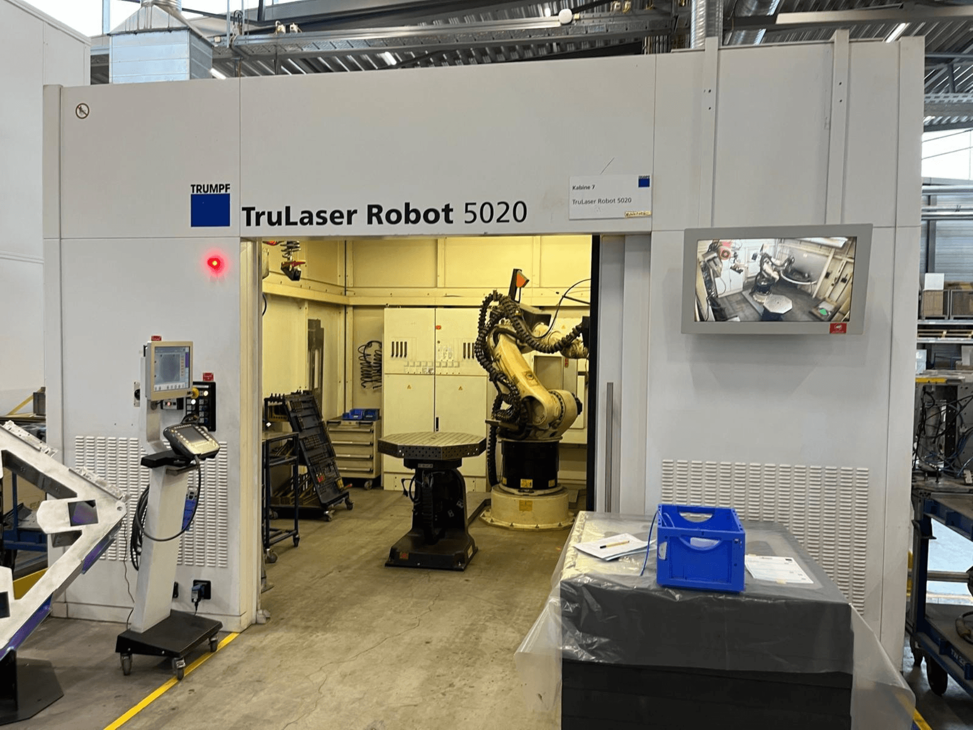 Stroj TRUMPF TruLaser Robot 5020 v průmyslovém prostředí, vybavený ovládacími prvky, robotickým ramenem a monitorem zobrazujícím probíhající operace.