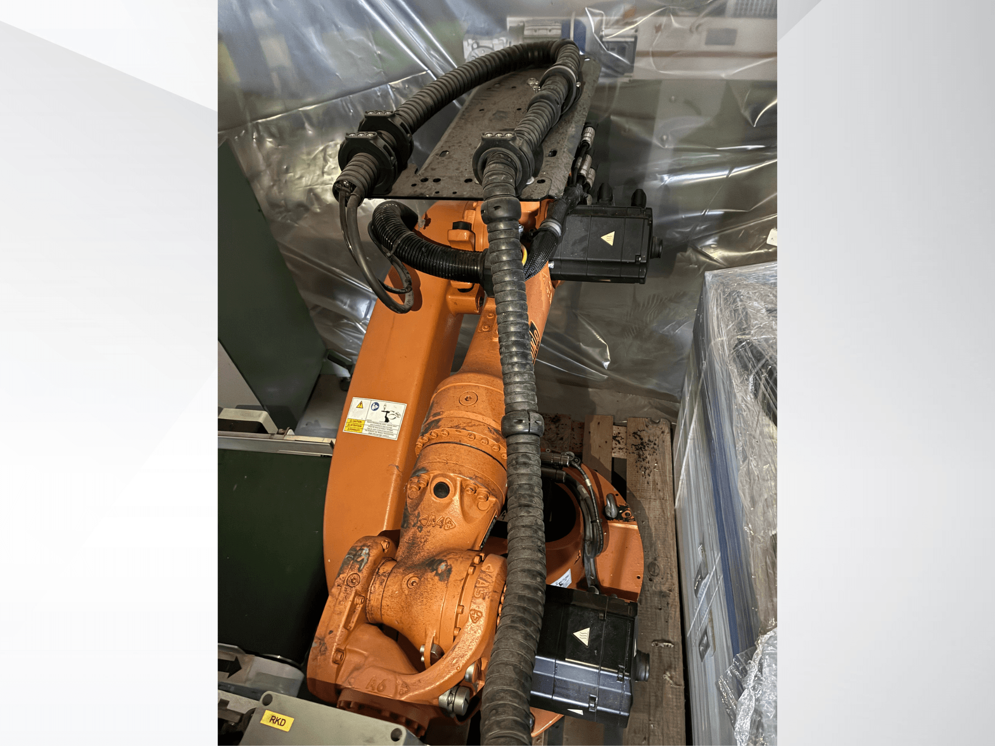 Robotické rameno KUKA KR16-2 v oranžové barvě, pohled shora, na kterém jsou vidět konektory a ochranné hadice.