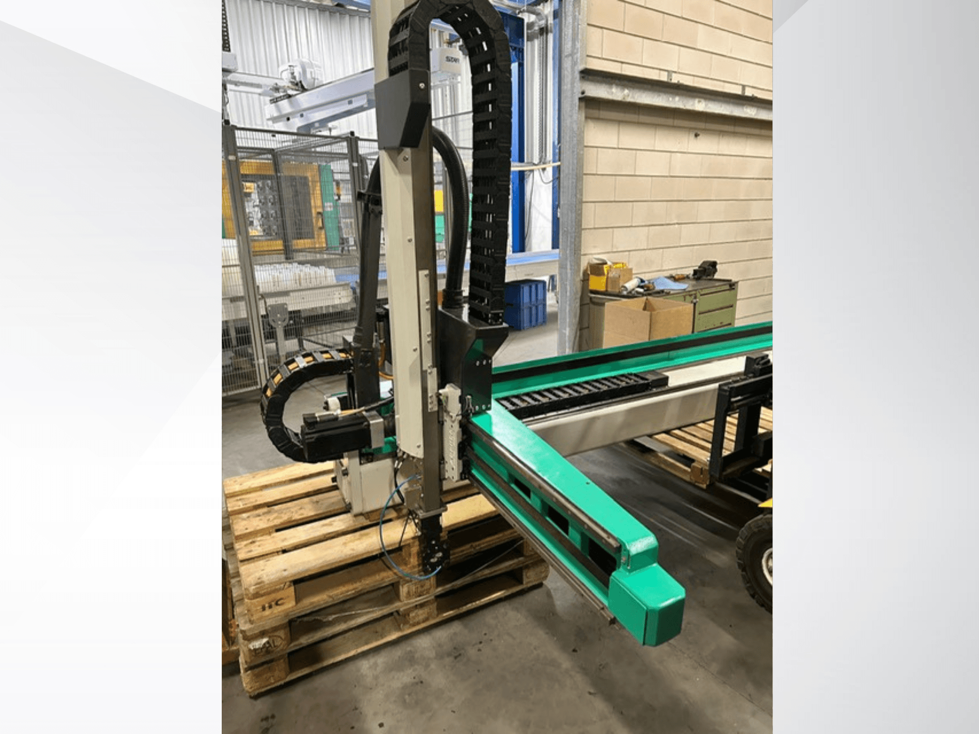 Arburg Multilift Select 15kg quer, boční pohled na systém manipulace s obrobky na dřevěných paletách, znázorňující robotické rameno a ovládací prvky.