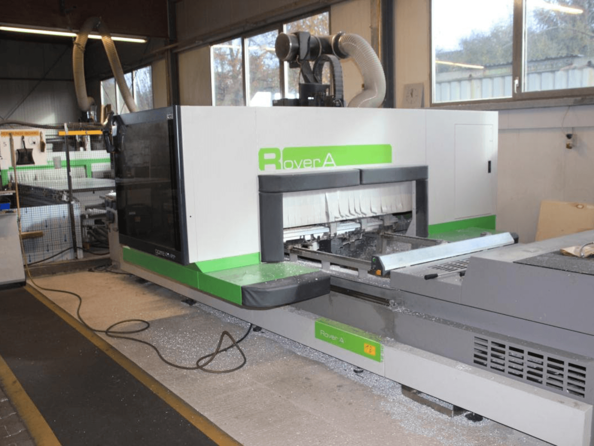 CNC frézka BIESSE Rover A 1232, boční pohled na řezný prostor a ovládací panel v průmyslovém prostředí.