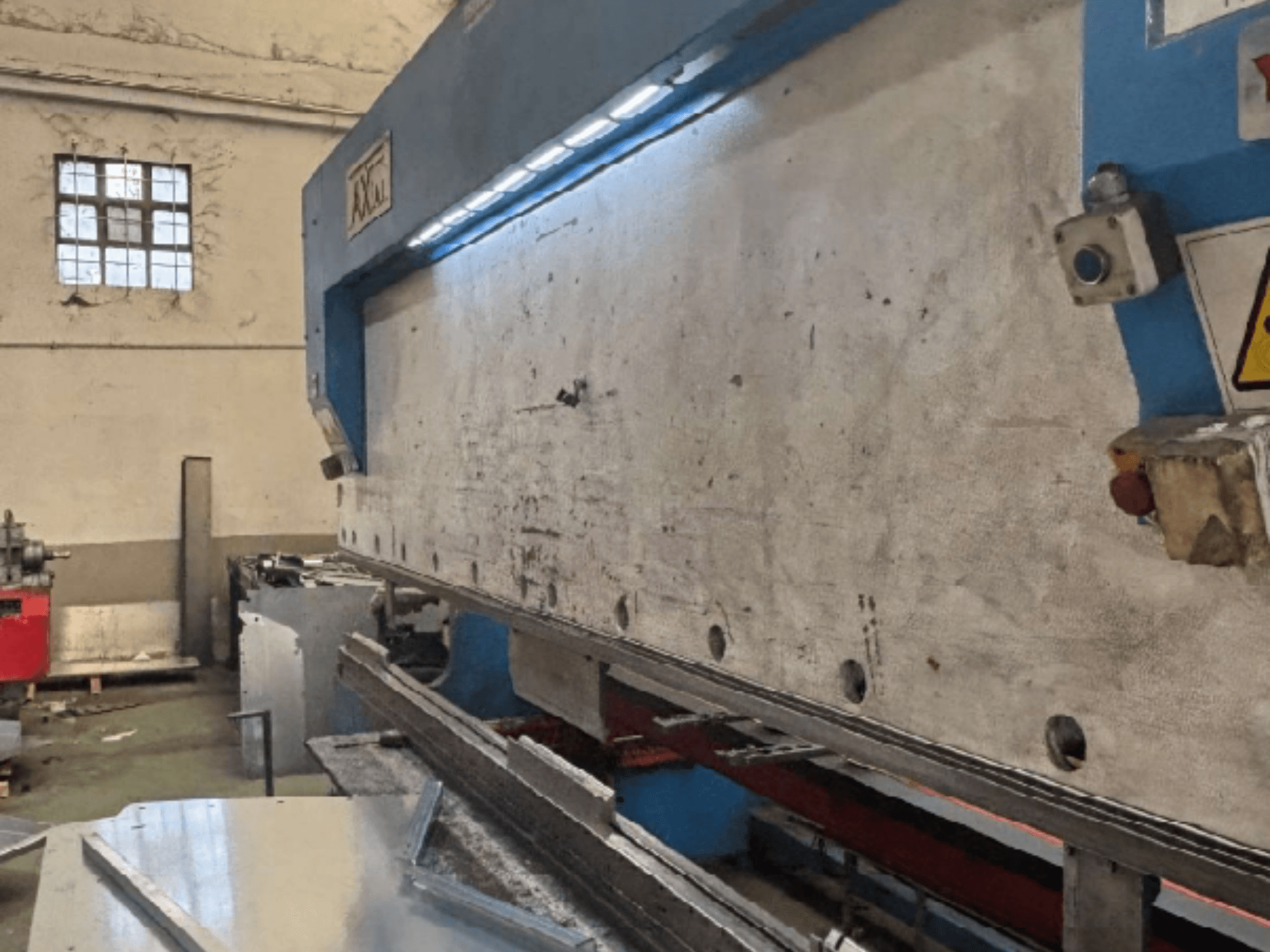 Manipulační systém Axial PHS-W-124 v dílně, boční pohled zobrazující pracovní plochu a detaily ovládacího panelu.