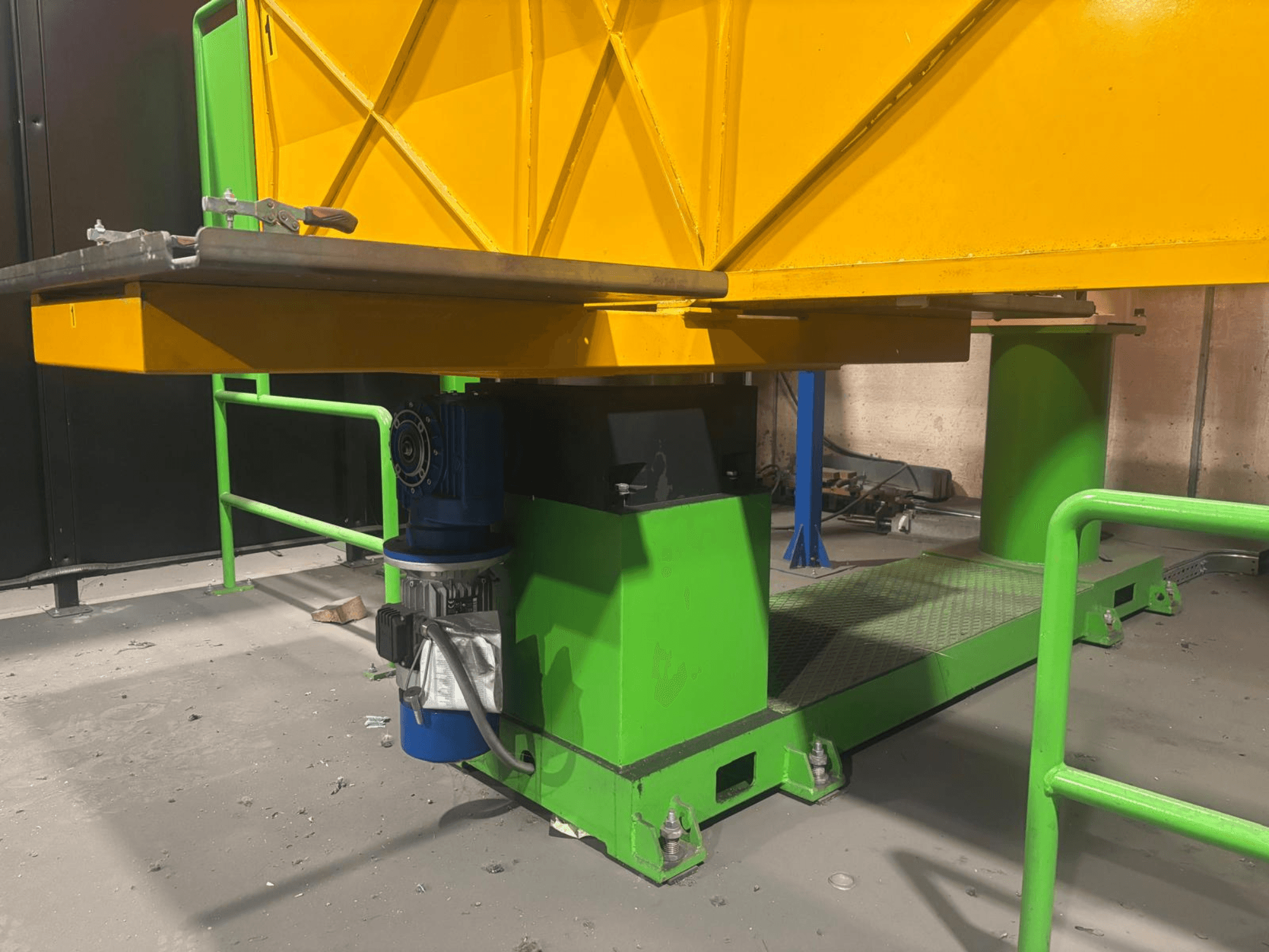 Zelenožluté průmyslové stroje z nízkého čelního pohledu s motorem a plošinou s texturovaným povrchem.