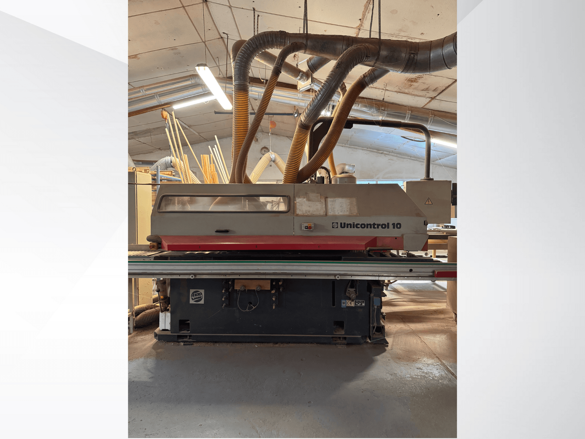 Pohled zepředu na dřevoobráběcí stroj Unicontrol 10 s trubkami pro odsávání prachu a ovládacími prvky.