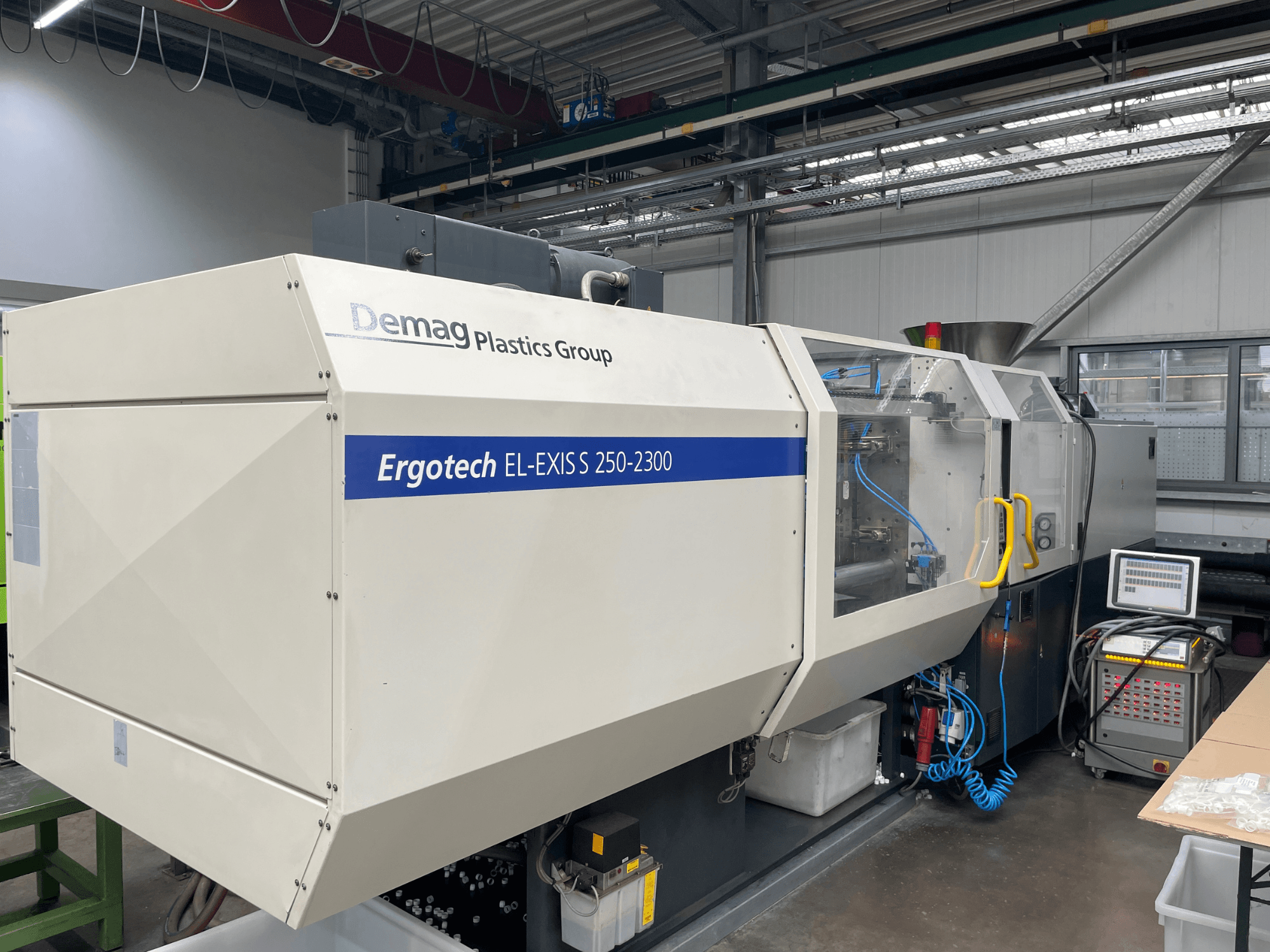 Vstřikovací stroj Demag Ergotech EL-EXIS S 250-2300, boční pohled, ukázka ovládacího panelu a podávacího systému.