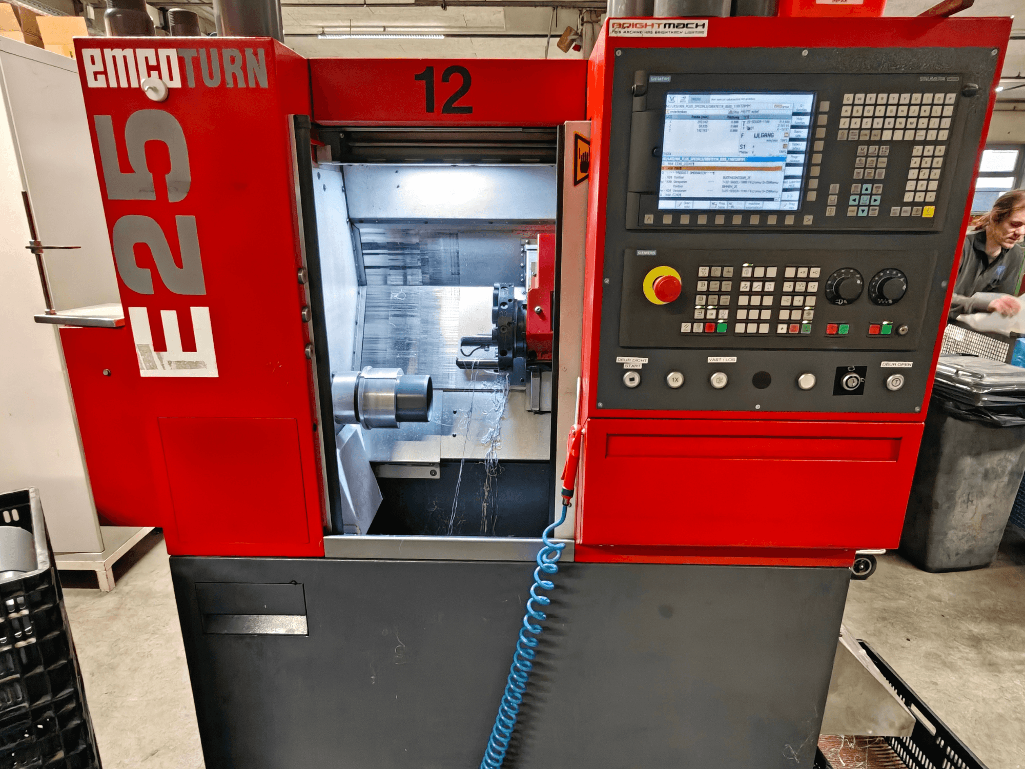 Pohled zepředu na stroj EMCO TURN E25, ovládací panel, držák nástrojů a vnitřní prostor s viditelným řezným nástrojem.