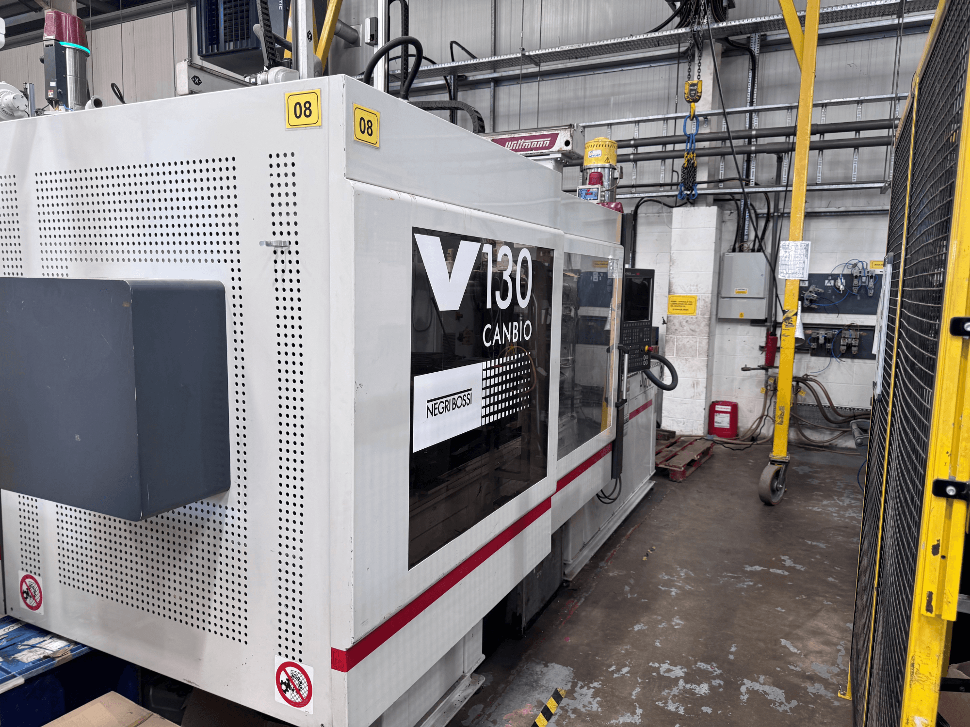 Hydraulický vstřikovací lis Negri Bossi 1300H-400, boční pohled, s ovládacím panelem a bezpečnostními značkami.