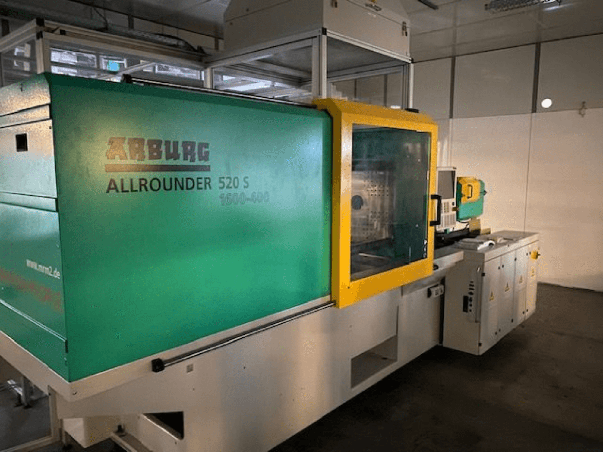 Vstřikovací stroj Arburg Allrounder 520 S, boční pohled, zelenožlutý exteriér, viditelné technické detaily.