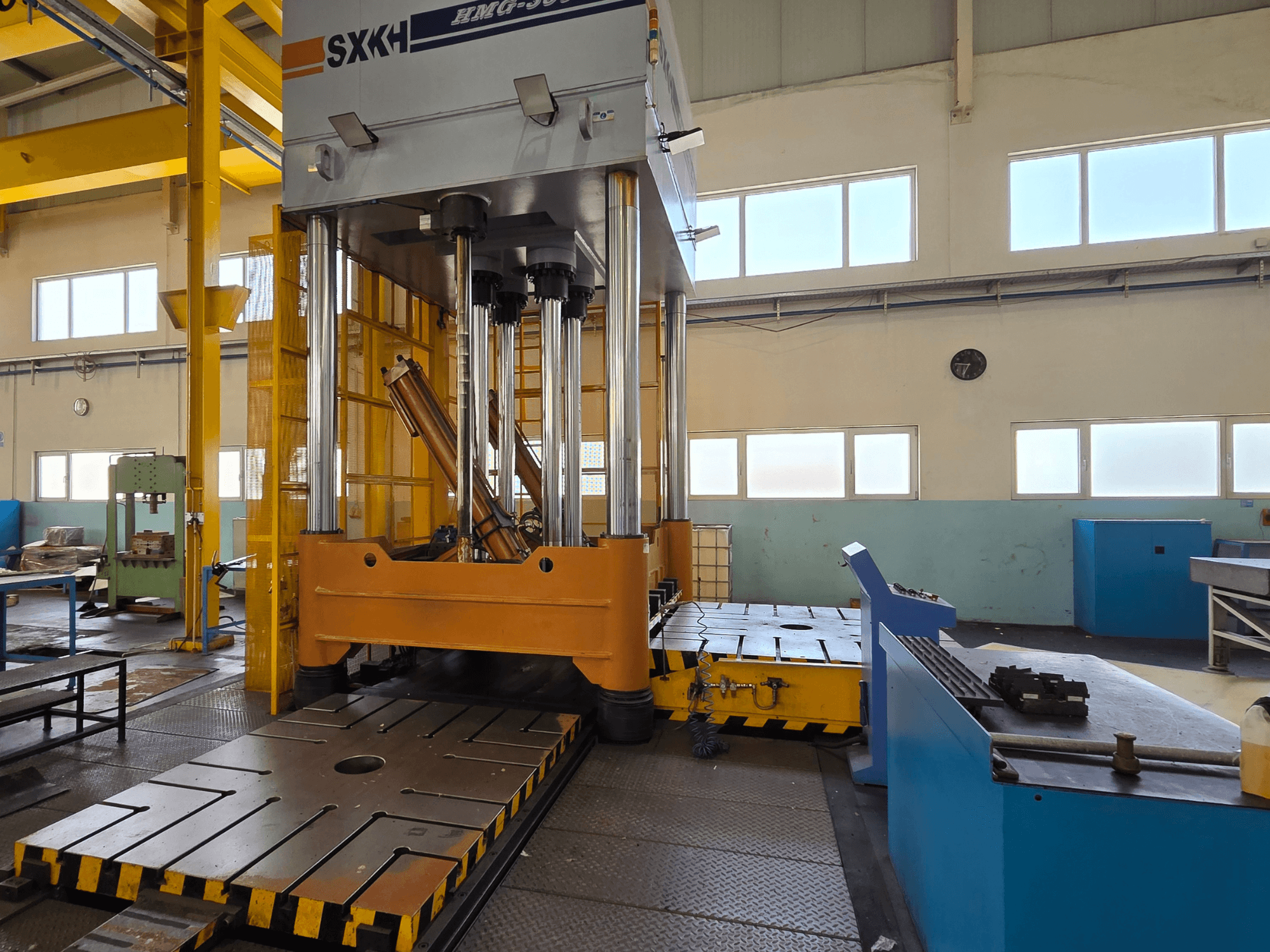 Hydraulický lis SXKH HMG-300JM s velkými lisovacími válci a robustní základnou v továrním prostředí.