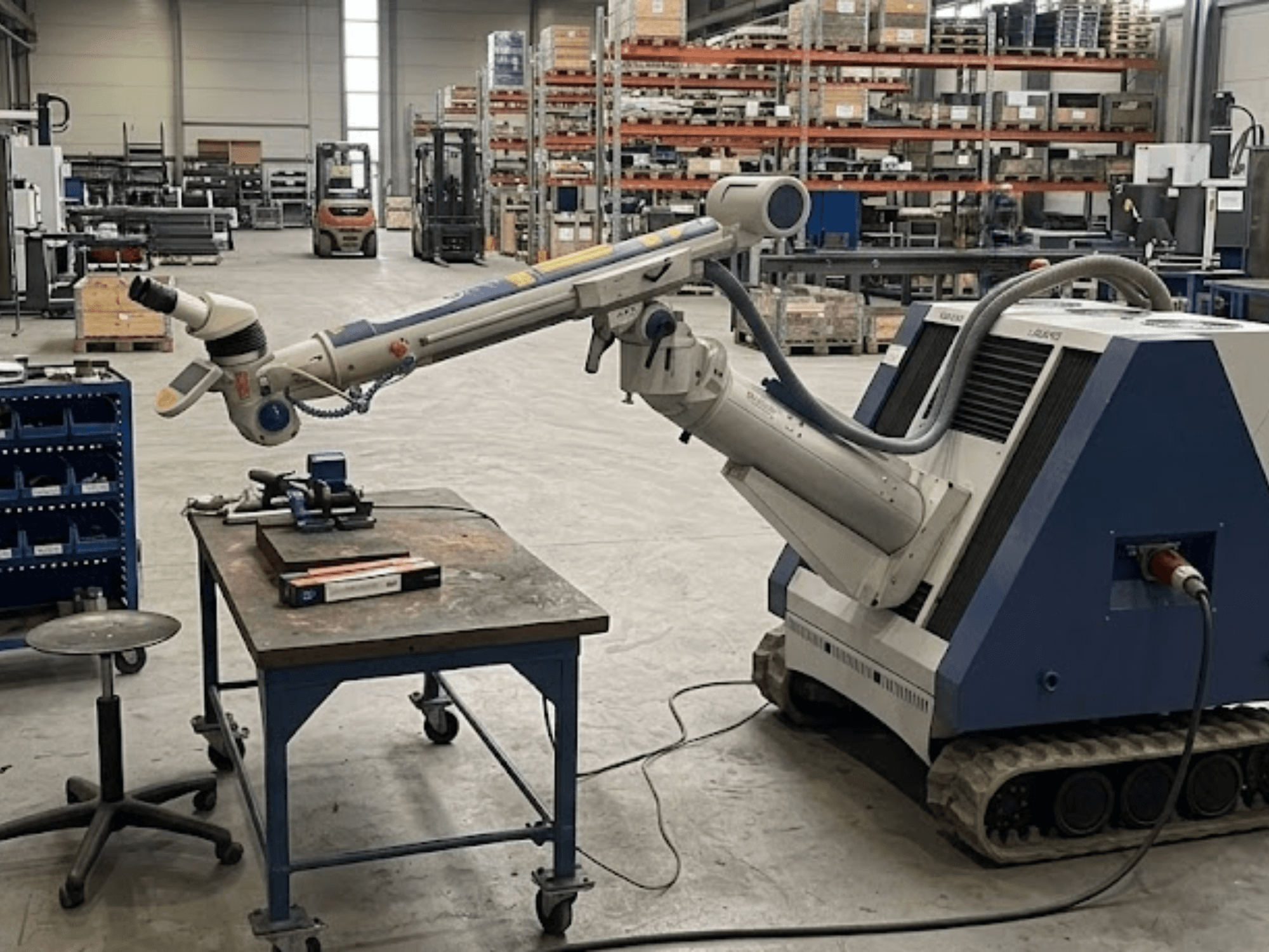 Obráběcí stroj ALPHA LASER ALFlak300 M v dílně s robotickým ramenem, pohled zepředu znázorňující přesné nastavení na pracovním stole.