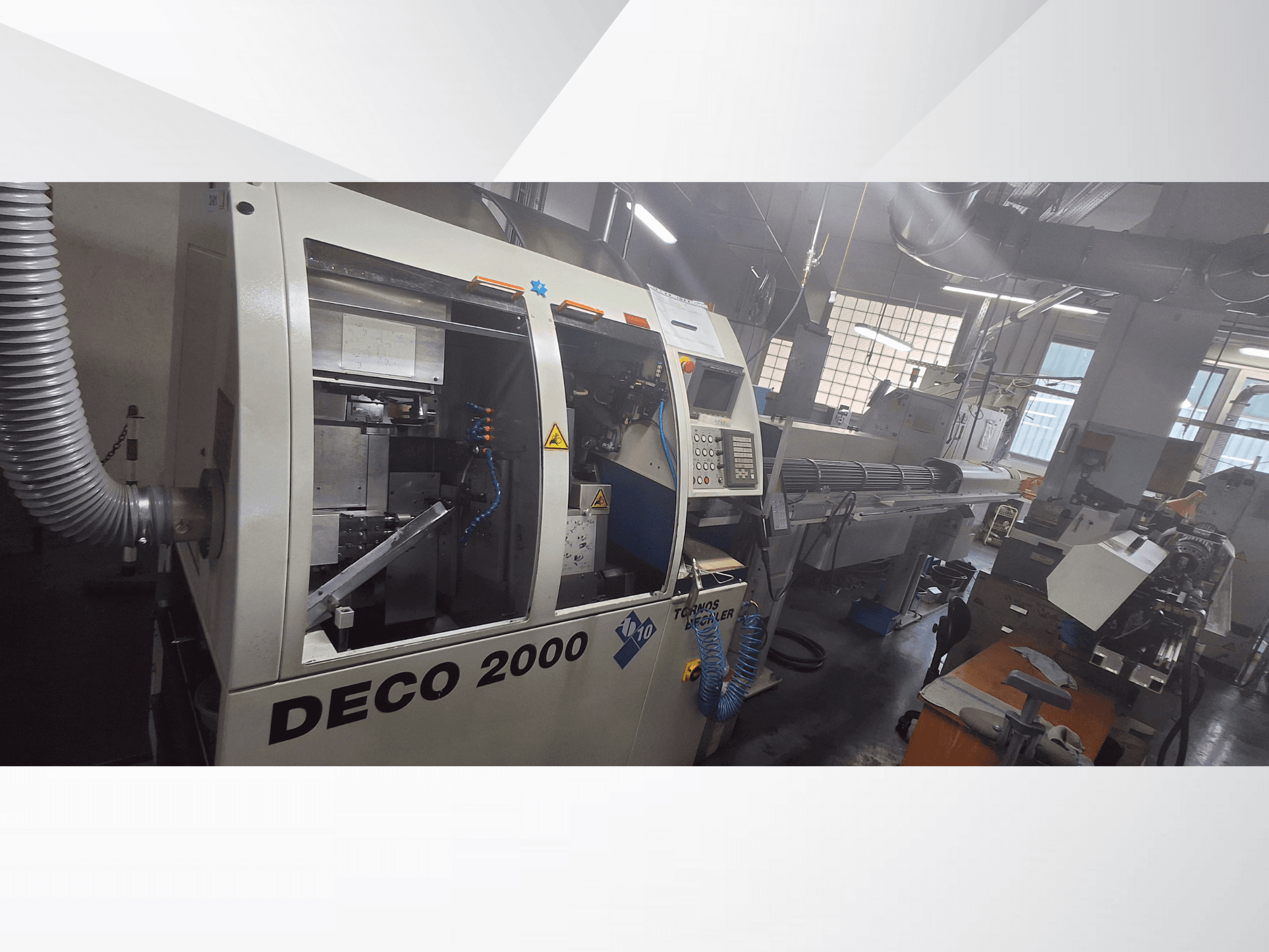 Stroj DECO 2000 CNC v dílně, pohled zepředu, ovládací prvky a dlouhé nastavení obrobku vpravo.
