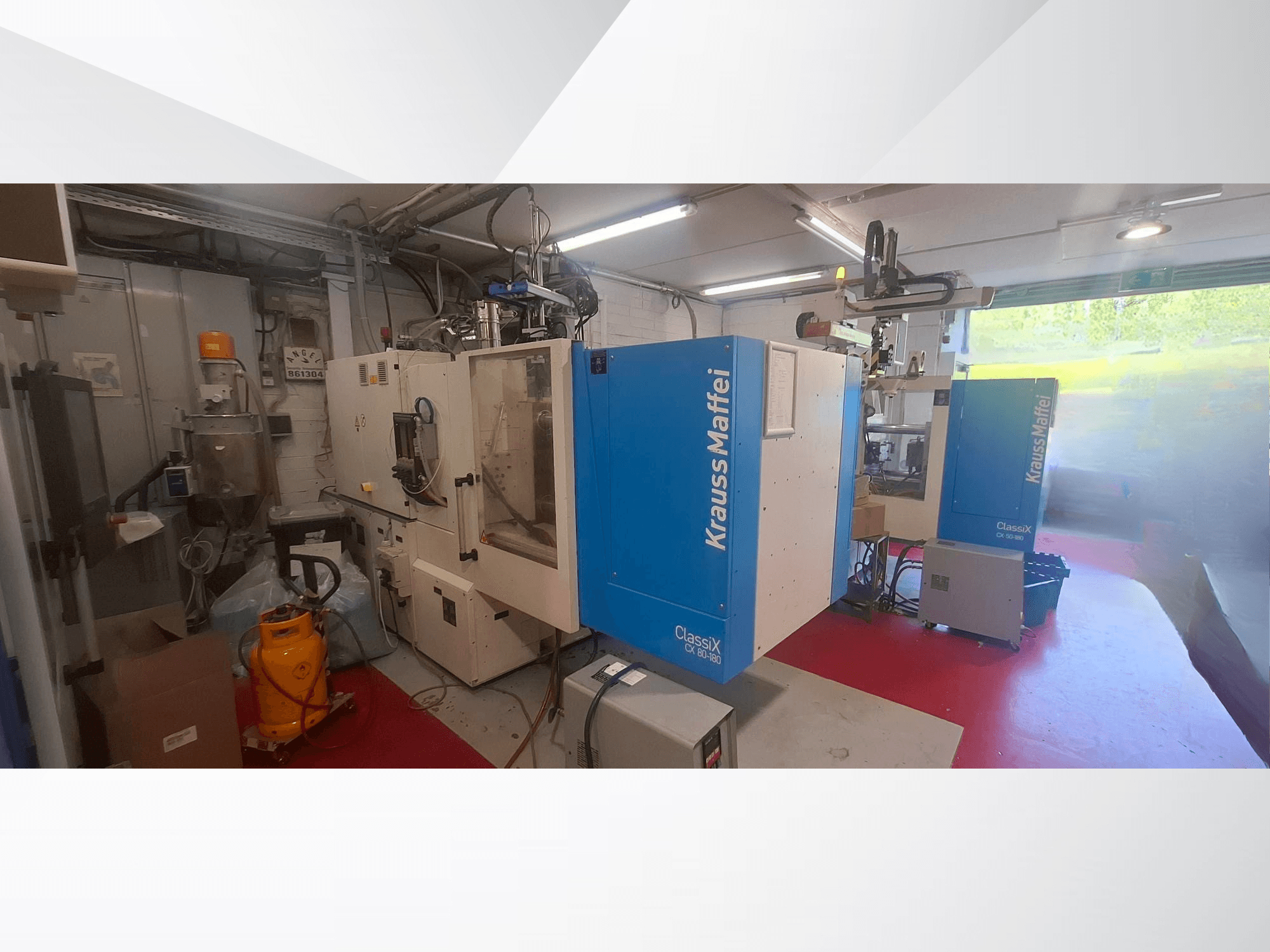 Hydraulický vstřikovací lis Krauss Maffei CX 80-180, pohled zepředu, v průmyslovém prostředí s okolním zařízením.