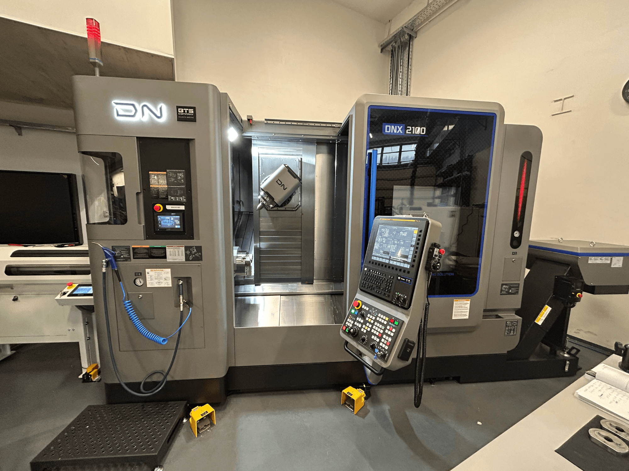 Stroj DN ONX 2100 CNC, pohled zepředu, ovládací panel, pracovní plocha a nástroj. Vybaveno bezpečnostním světlem a kontrolkami provozu.