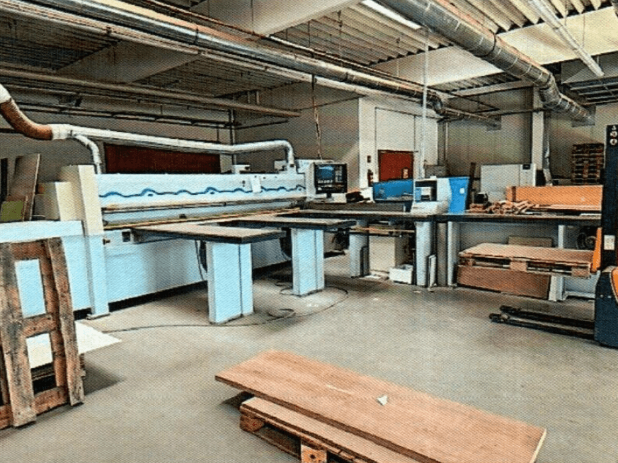 Desková pila HOMAG HPL 11/38/22 v dílně s velkým řezacím stolem a zobrazovací konzolou, pohled zepředu.