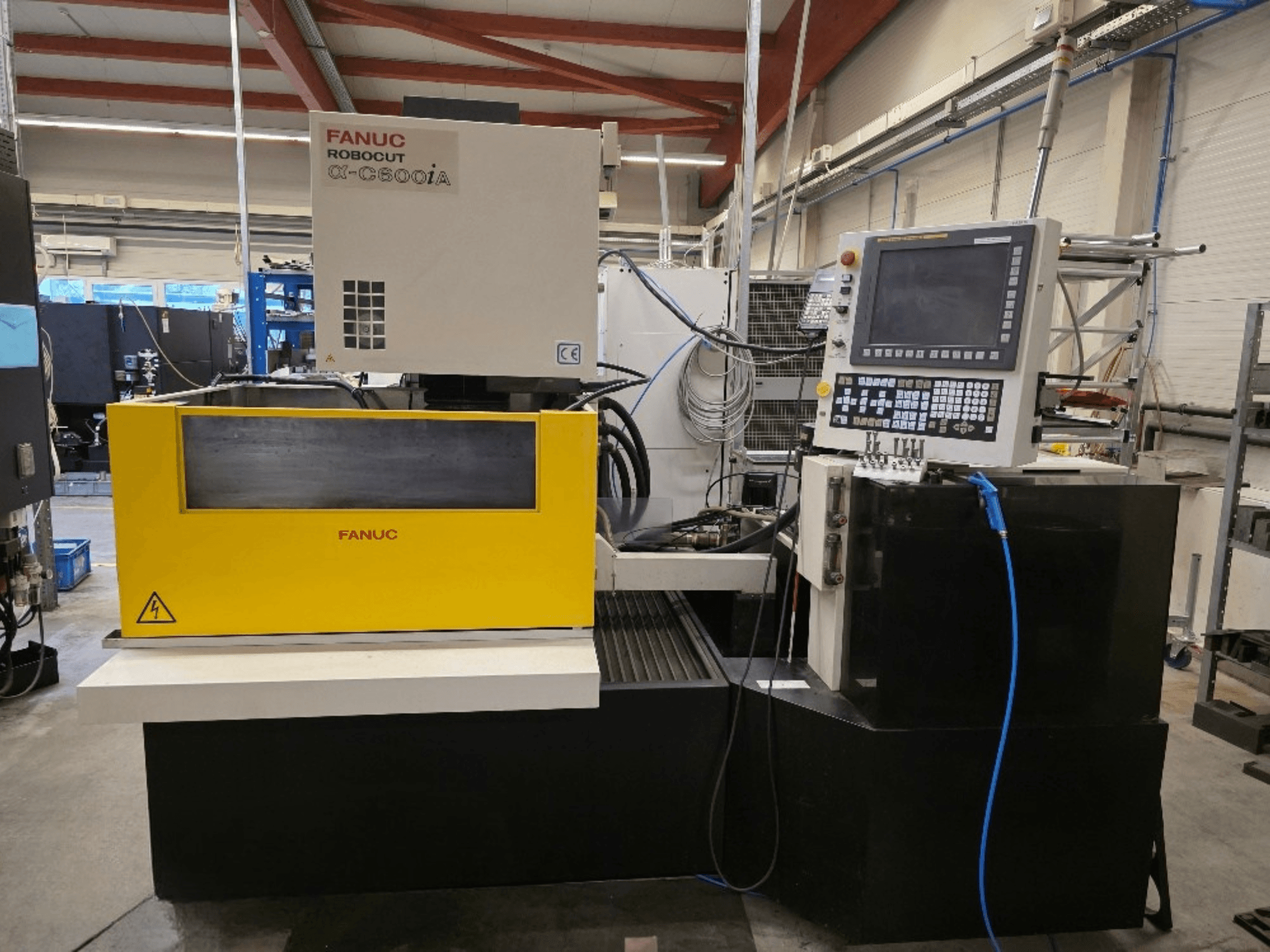 Drátový řezací stroj FANUC Robocut α-C600iA, pohled zepředu, se žlutým ovládacím panelem a digitálním displejem.
