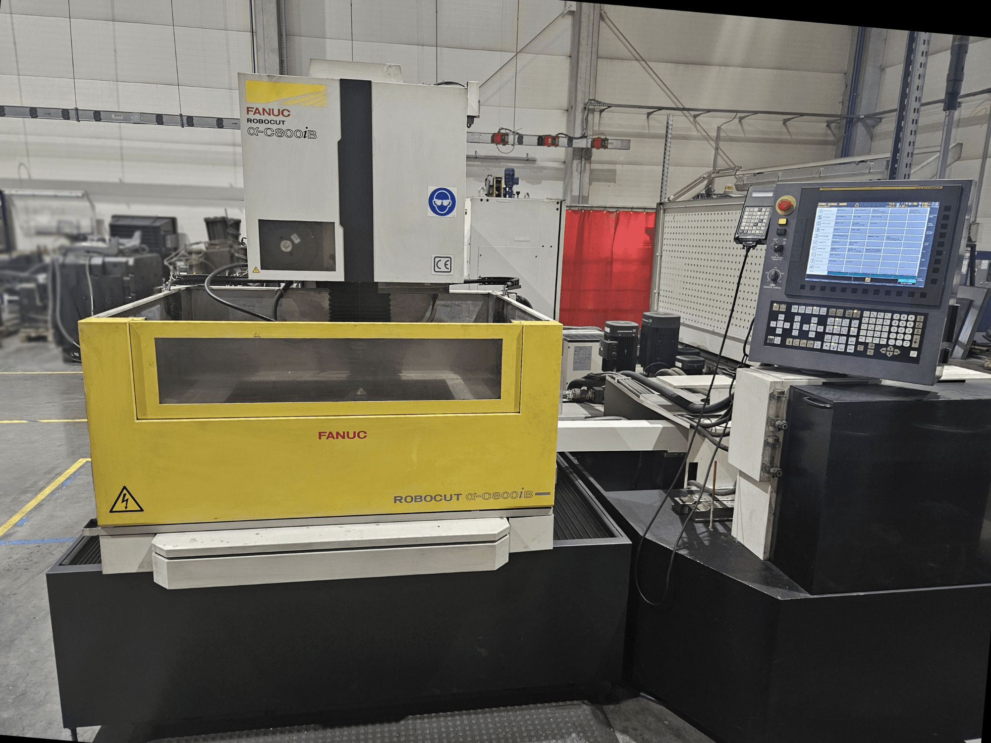 Pohled zepředu na stroj FANUC Robocut α-C600iB se žlutým a šedým tělem stroje, ovládacím panelem CNC a provozním displejem.