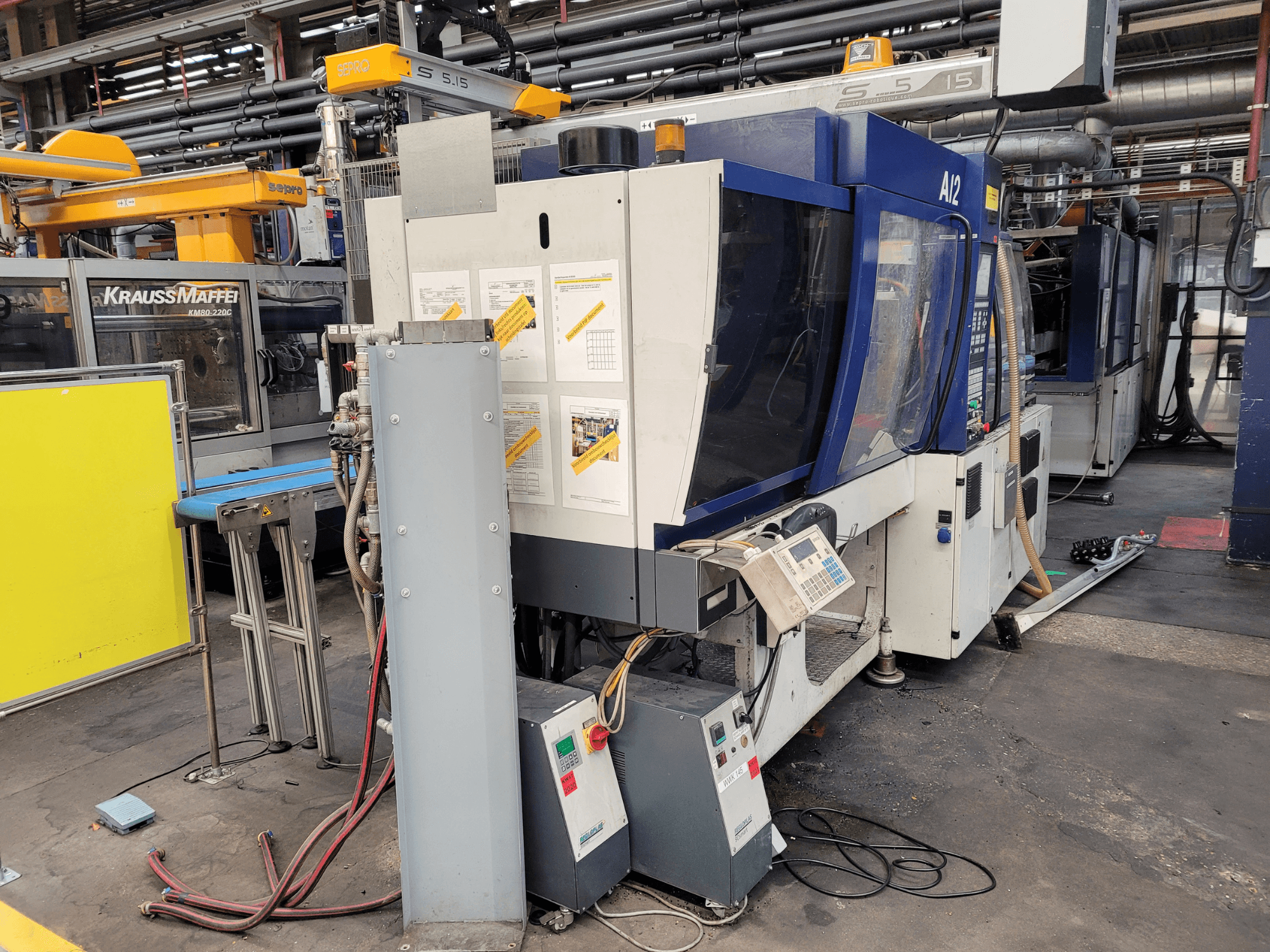 Vstřikovací stroj KraussMaffei model KM80-232G, pohled zepředu, s ovládacím panelem a provozními prvky.