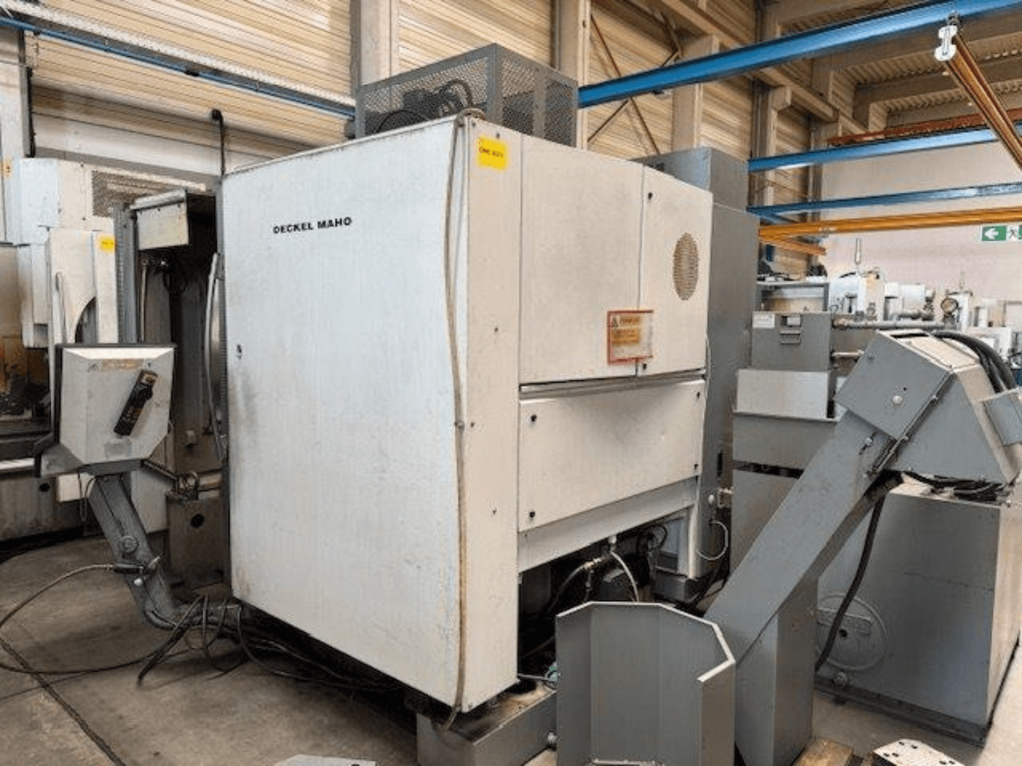 Vertikální obráběcí centrum DECKEL MAHO DMC 100 V, boční pohled s viditelným ovládacím panelem a různými nástavci.