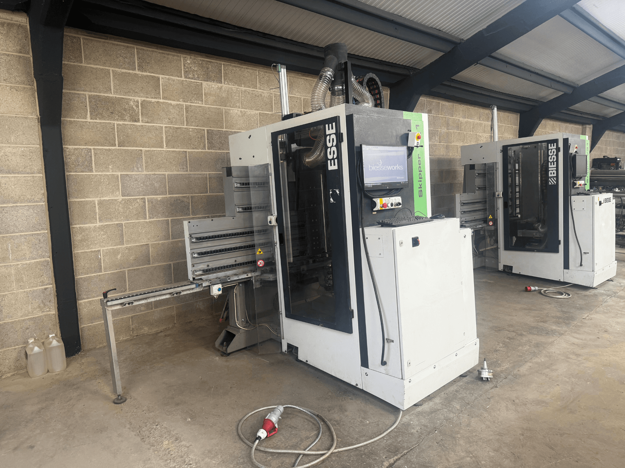 Vyvrtávačka dřeva BIESSE Skipper v31 v bočním pohledu, s ovládacím panelem a přilehlými stroji, v dílně.